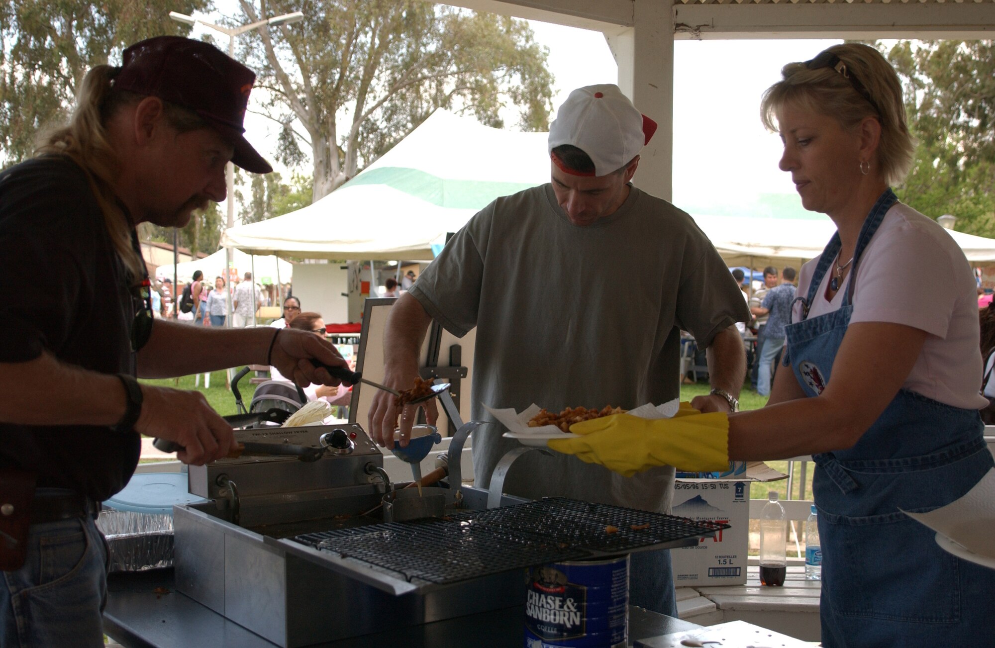 Mike Shrope, left, and Lt. Col. Mike Platt, middle, make funnel cakes during the Spring fling on April 14.  Ann Taylor, right, takes the finished funnel cakes and gives them to customers.   The Spring Fling was held at Arkadas Park and included pony rides, face painting, food booths, and games.  (U.S. Air Force photo by Airman First Class Tiffany A. Colburn)