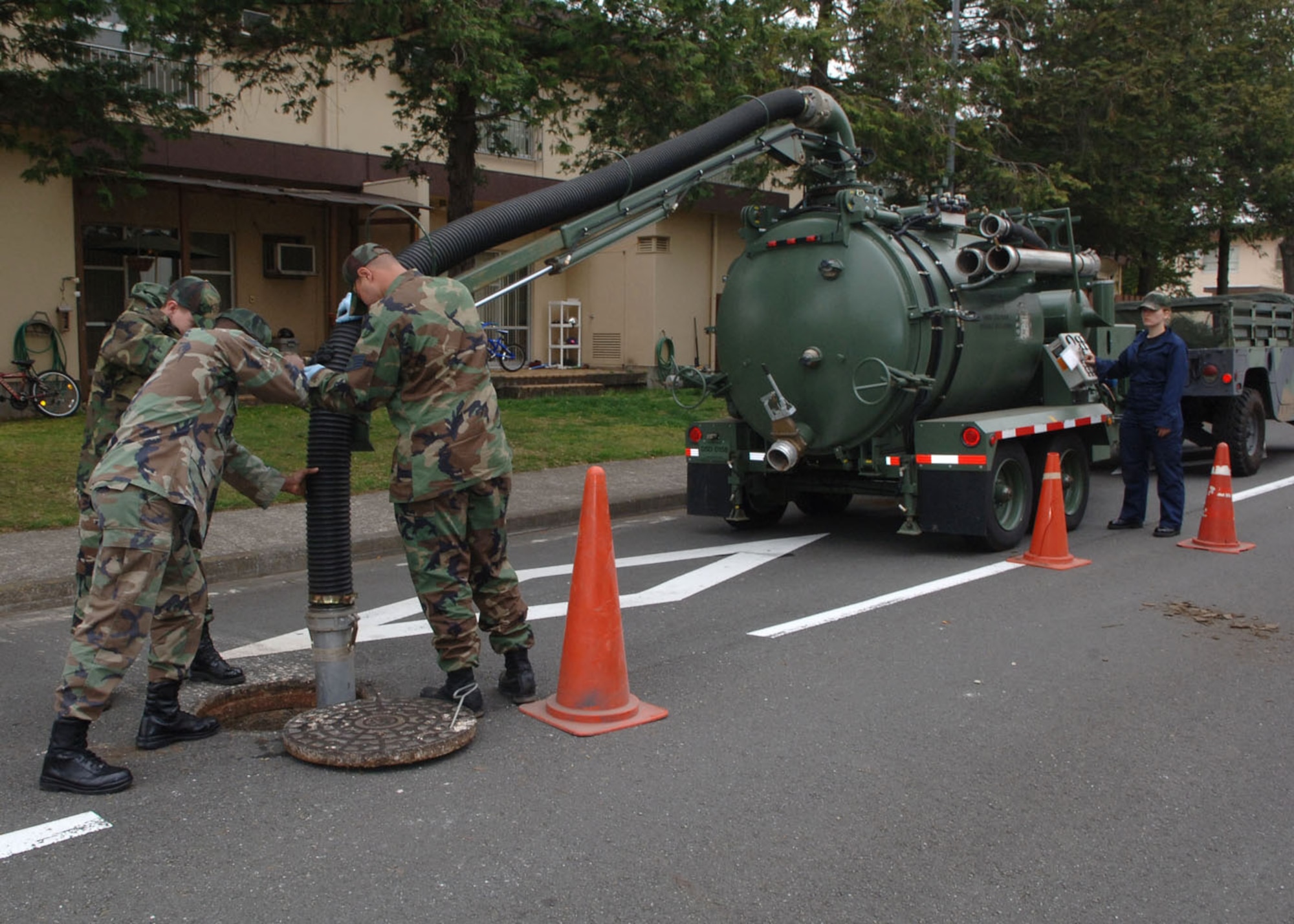 Airman from the 374th Civil Engineer Squadron unclog a manhole on Yokota Air Base that is full of cooking grease and oil from residents pouring thses liquids down the drains. (Air Force photo by Senior Airman Veronica Pierce VIRIN 070402-F-3177P-064)