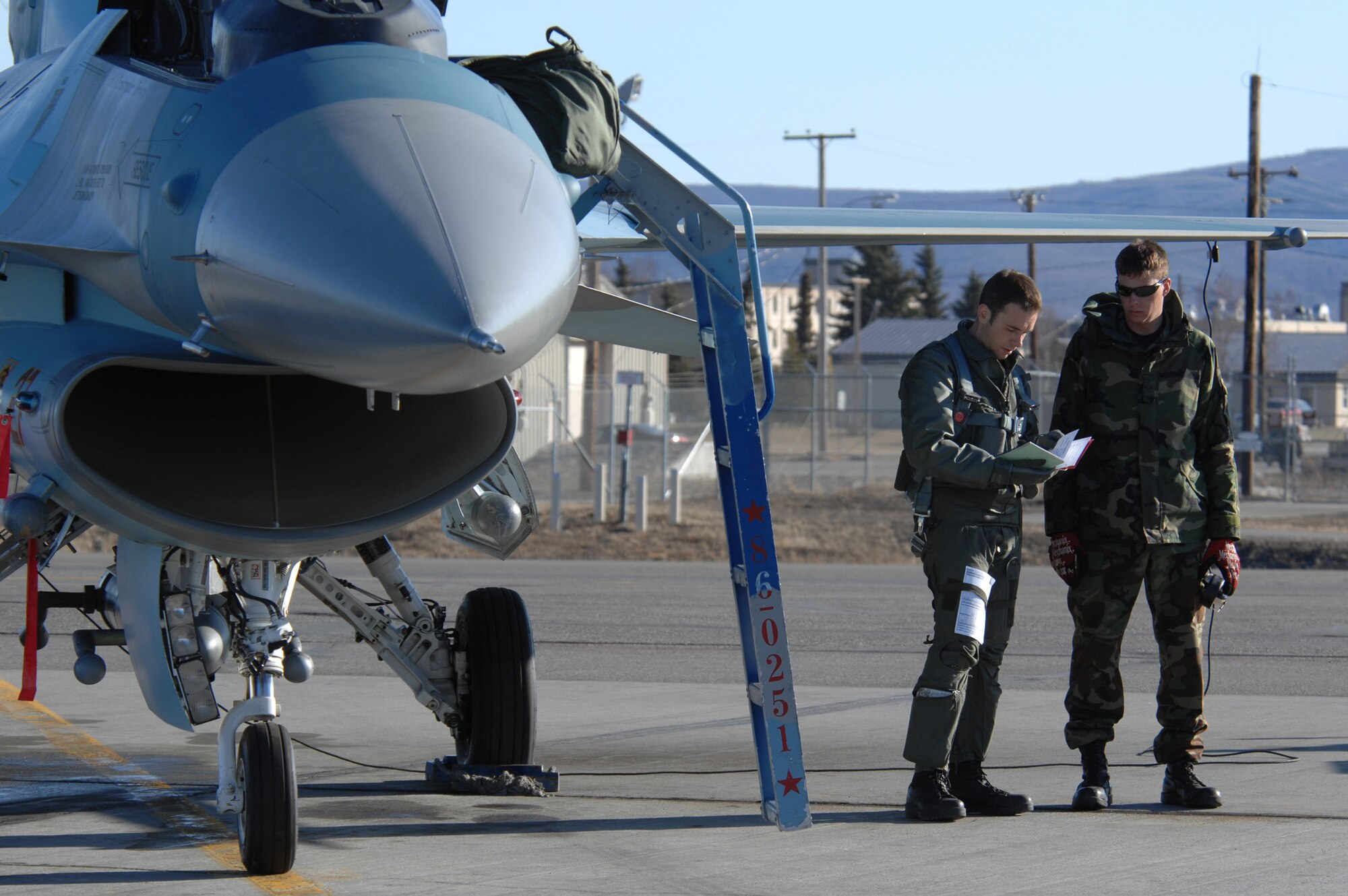 EIELSON AIR FORCE BASE, Alaska -- An F-16 Fighting Falcon pilot from the 64th Aggressor Squadron, Nellis Air Force Base, Nevada consults with his crew chief prior to a mission during Red Flag-Alaska 07-1. Red Flag-Alaska is a Pacific Air Forces-directed field training exercise for U.S. forces flown under simulated air combat conditions. It is conducted on the Pacific Alaskan Range Complex with air operations flown out of Eielson and Elmendorf Air Force Bases. (U.S. Air Force Photo by Staff Sgt Joshua Strang)