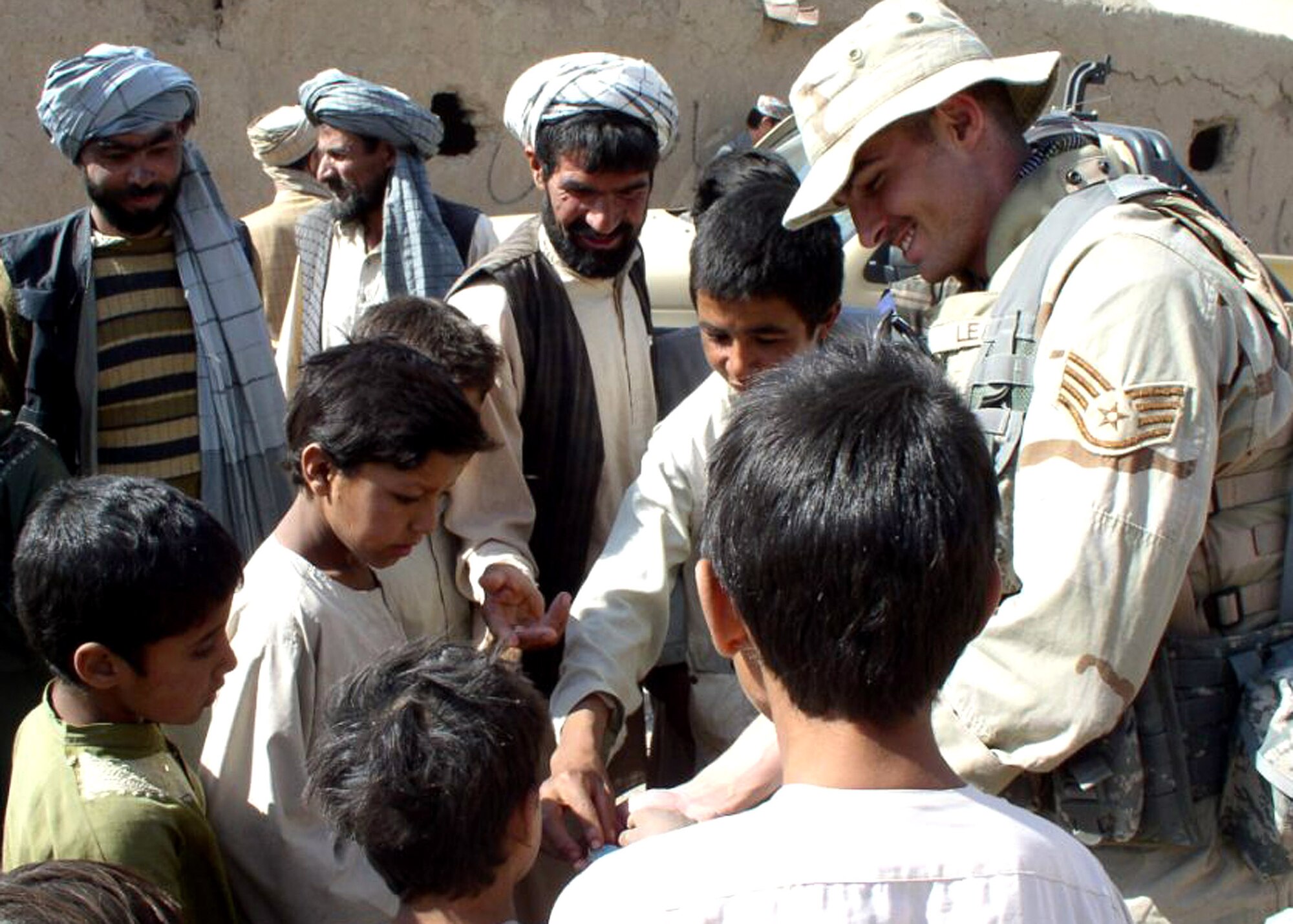 Staff Sgt. Matthew Leas shares treats with children in Bazergan, Afghanistan, during an Afghan National Army recruiting mission to the village in the summer of 2006. The 364th Recruiting Squadron systems administrator deployed to Forward Operating Base Camp Stone where he served with the ANA 207th Zafar (Victory) Corps as an embedded tactical trainer for public affairs and recruiting. In six months, the NCO and the 207th traveled to about 100 villages recruiting more than 700 men. (U.S. Air Force photo)
