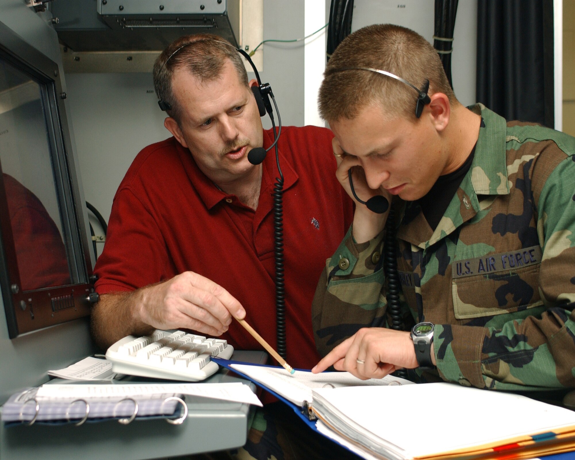 Instructor Michael Bolstad, left, directs Airman Basic Aaron Wimberley through the steps of surveillance operations at an operator console unit workstation in Bryan Hall.
(U.S. Air Force Photo by Kemberly Groue)

