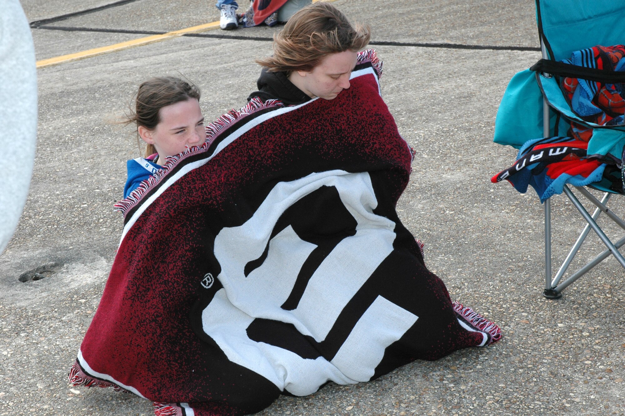 EGLIN AIR FORCE BASE, Fla. -- Victoria Shire and Morgan Peterson, both Eglin residents, bundle up underneath a blanket April 15 during the 2007 Eglin Air Show. The first day of the air show was cancelled due to severe weather coming into the area. Although the second day was cold and windy, more than 42,000 spectators braved the elements to watch the aerial acrobatics in the skies over Eglin. (U.S. Air Force photo by Staff Sgt. Mike Meares)