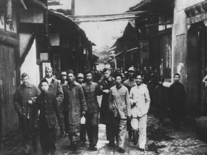 Chinese and American comrades at arms-Chinese soldiers bring in a group of General Doolittle’s Tokyo raiders to the tiny village near where their bomber crashed. Center right, his arm held by a Chinese is Col. John Hilger, who was injured. (National Archives, US Navy 80-G-063593).