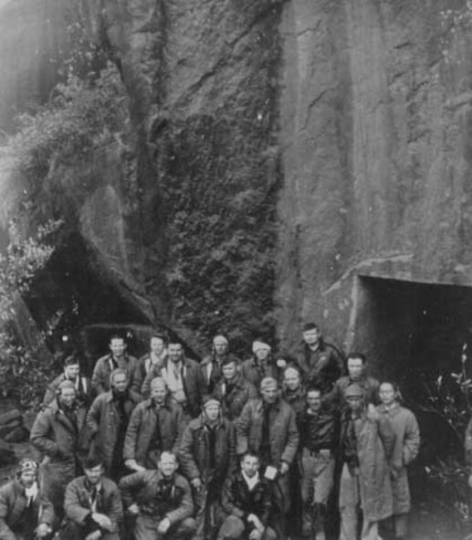 Doolittle’s men require air raid shelter too. Major General James Doolittle’s Tokyo raiders are grouped outside this shelter carved from the mountainside. They lived here for 10 days after assembling from their Chinese mountain retreats. Japanese planes raided nearby villages frequently. (National Archives, Army Airforce BUAER 63586).