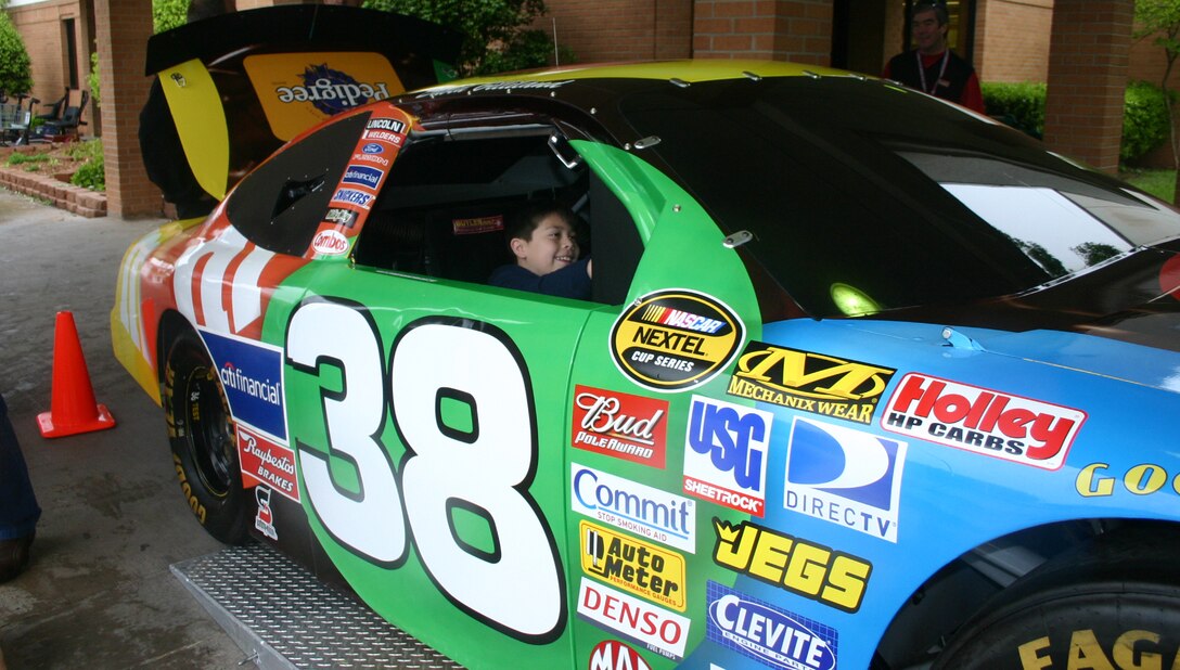 Andrew Hernandez enjoys a spin in the M&M #38 Ford Fusion on display at the Sheppard Commissary April 17.  The car, retired from NASCAR racing, has been converted into a computer racing game. (U.S. Air Force photo/Staff Sgt. Tonnette Thompson) 
