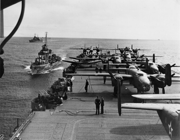 PACIFIC OCEAN 1942 -- Some of the B-25 Mitchells of the Doolittle Raiders crowd the rear deck of the USS Hornet with two escort vessels following close in the background. The B-25s took up most of the deck space of the USS Hornet, so the Navy fighters were stored below on the hangar deck. The USS Enterprise (not seen) provided fighter cover for the task force. The Doolittle Raid, U.S. Army Air Force special order #1 of World War II, was a daring one-way mission of 16 B-25 Mitchell medium bombers with 80 aircrew, commanded by Lt. Col. James "Jimmy" Doolittle, to carry out America's first offensive attack on Japan. (Photo courtesy National Museum of the U.S. Air Force) 