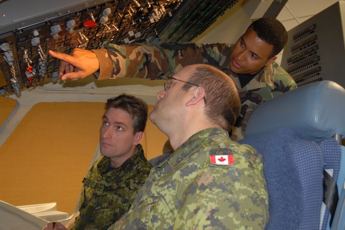 Tech. Sgt. Michael Roberts, 373rd Training Squadron Detachment 5 communication, navigation and mission systems instructor, explains what Cpl. Steve Hart and Sergeant Maurice Dorrington, Royal Canadian Air Force 429th Squadron avionics technicians, should look for on the electrical panel as they apply electrical power to the aircraft. (U.S. Air Force photo/Airman Melissa Harper)