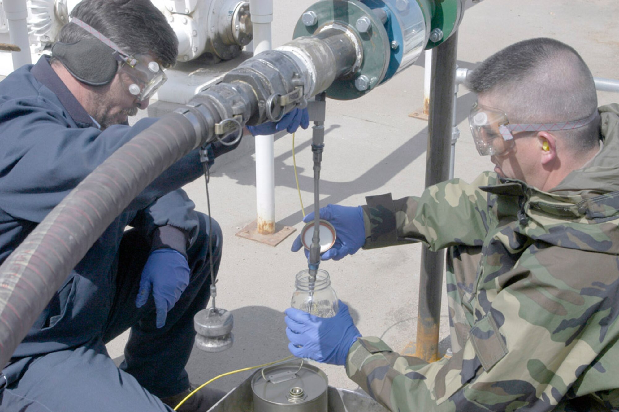 Tech. Sgt. Robert Leigh, 90th Logistics Readiness Squadron, and Chris Shafer, Phoenix Management Inc., pump E85 fuel, gasoline composed of 85 percent ethanol, into a glass jar for examination at the military service station April 5. E85, a bio-based, renewable fuel made from corn, uses less fossil fuels than traditional gasoline. Ethanol fuel can reduce carbon dioxide emissions, a major contributor to global warming. Carbon dioxide is released during ethanol production and combustion but it can be absorbed as a nutrient used by the crops  that produce it. It is also non-toxic, biodegradable and water-soluble. This is Warren's first E85 fuel delivery (Photo by 2nd Lt. Lisa Meiman).