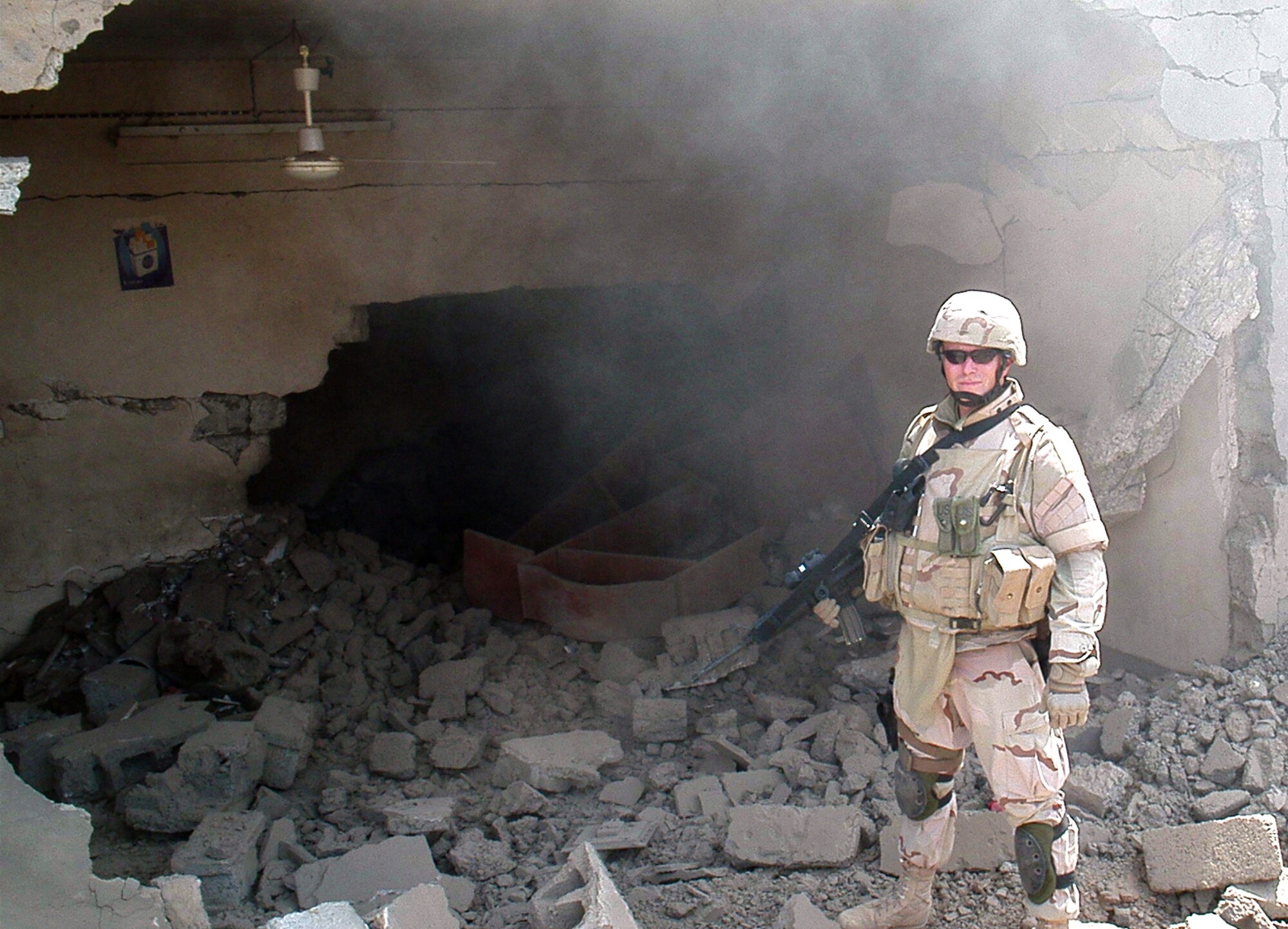 SOUTWEST ASIA - Tech. Sgt. David Ewbank poses in front of a demolished weapons cache.  The building was the trap-laden home of an insurgent who also used it to store weapons.  Upon finding the traps, Sergeant Ewbank was given permission to destroy the house. (U.S. Air Force photo/Senior Master Sgt. Dale Griffin)