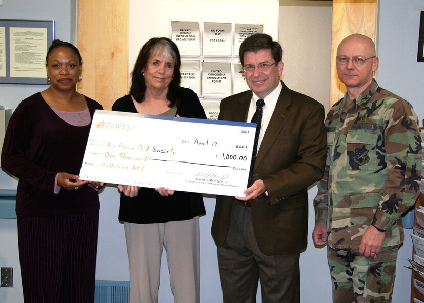 Mr Rick Essick, TRIWEST Healthcare Alliance, presents a $1,000 check for the Air Force Aid Society to Ms. Lenn Furrow, Airman and Family Readiness Center. TRIWEST is the 49th Medical Group's partner in providing medical services to the Holloman community. (U.S. Air Force photo courtesy of the 49th Medical Group)