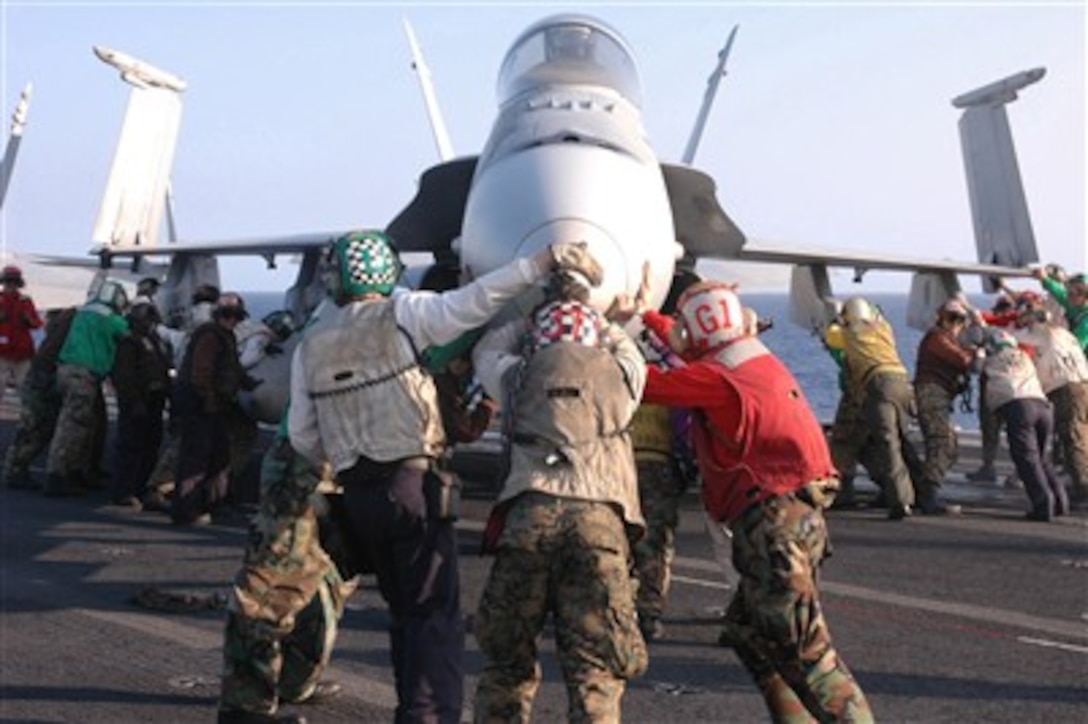 U.S. Navy sailors and Marines perform a push back on an F/A-18A Hornet aircraft on the flight deck of the nuclear-powered aircraft carrier USS Nimitz (CVN 68) on April 11, 2007.  The Nimitz Carrier Strike Group is deployed in the Pacific Ocean in support of operations in the U.S. Central Command area of responsibility.  