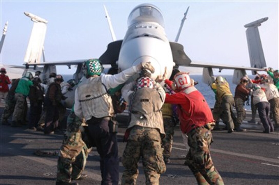 U.S. Navy sailors and Marines perform a push back on an F/A-18A Hornet aircraft on the flight deck of the nuclear-powered aircraft carrier USS Nimitz (CVN 68) on April 11, 2007.  The Nimitz Carrier Strike Group is deployed in the Pacific Ocean in support of operations in the U.S. Central Command area of responsibility.  