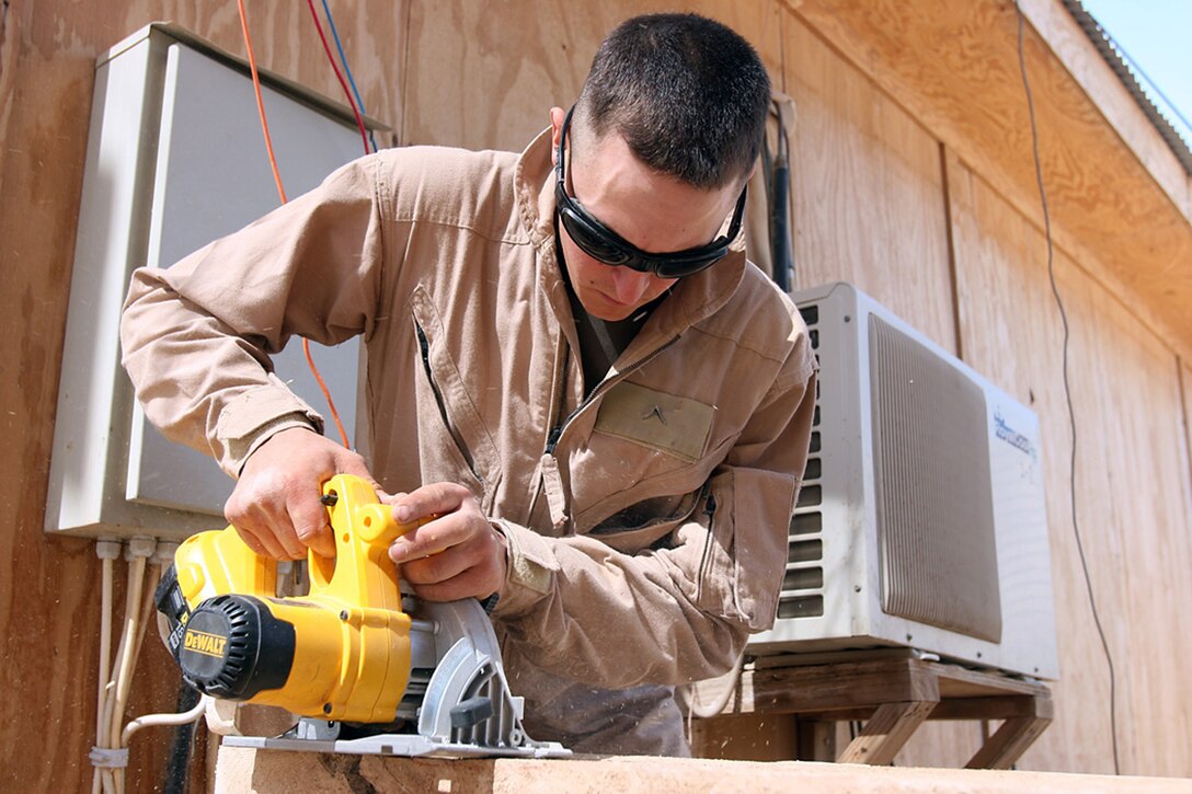 COMBAT OUTPOST RAWAH, IRAQ – Pfc. Jon E. Combs, the assistant police sergeant with 1st Light Armored Reconnaissance Battalion, Regimental Combat Team 2, uses a saw to cut new boards for a new portion of walkway outside the battalion’s Combat and Operations Center. Combs has spent most of his time during the past two months improving various areas of the battalion’s camp. Official Marine Corps Photo By Cpl. Ryan C. Heiser.