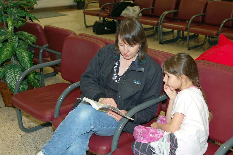 Burnadette Walkins reads to her daughter, Adriana, as they wait for a space-available flight from Dover Air Force Base, Del., to Ramstein Air Base, Germany. Mrs. Walkins is the wife of Army Lt. Col. Paul Walkins, stationed at Stuttgart, Germany. (U.S. Air Force photo/Tech. Sgt. Kevin Wallace)