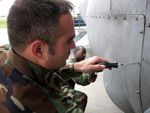 Tech. Sgt. Tony Sybirski, a C-130 engine mechanic, and crew chief Airman 1st Class Nicholas Heyward work together to close a panel on a C-130 Globemaster III April 17 at Yokota Air Base, Japan. Sergeant Sybirski and Airman Heyward are assigned to the 374th Airlift Wing Maintenance Squadron. (U.S. Navy photo/Petty Officer 3rd Class Jason Segedy)