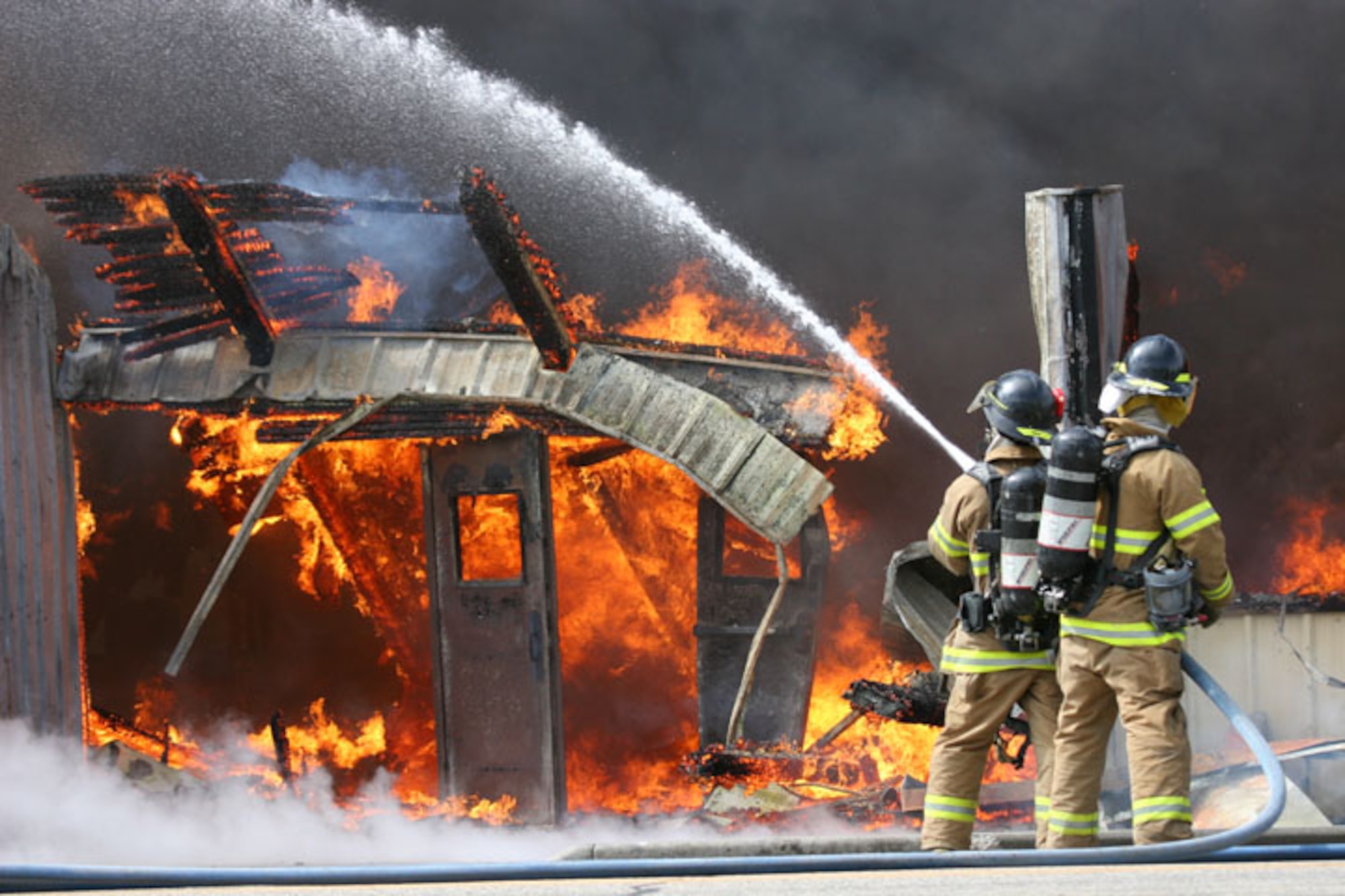 MOUNTAIN HOME AIR FORCE BASE, Idaho -- Firefighters here combat a controlled fire at Bldg. 1612 April 12. Already scheduled for demolition, the fire department used the building to train its fire fighters with the final burn bringing down the entire structure April 12. Air Force photo by Tech. Sgt. Doug Richardson