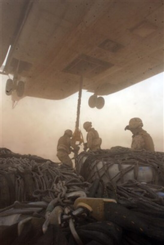 U.S. Marines work under a hovering CH-53E Super Stallion helicopter as they attach cargo nets of water and Meals, Ready to Eat for an external re-supply lift from Al Asad Air Base, Iraq, to Regimental Combat Team 2 at Camp Timber Wolf, Iraq, on April 10, 2007.  The Marines are assigned to Helicopter Support Team, Combat Logistics Battalion 2.  