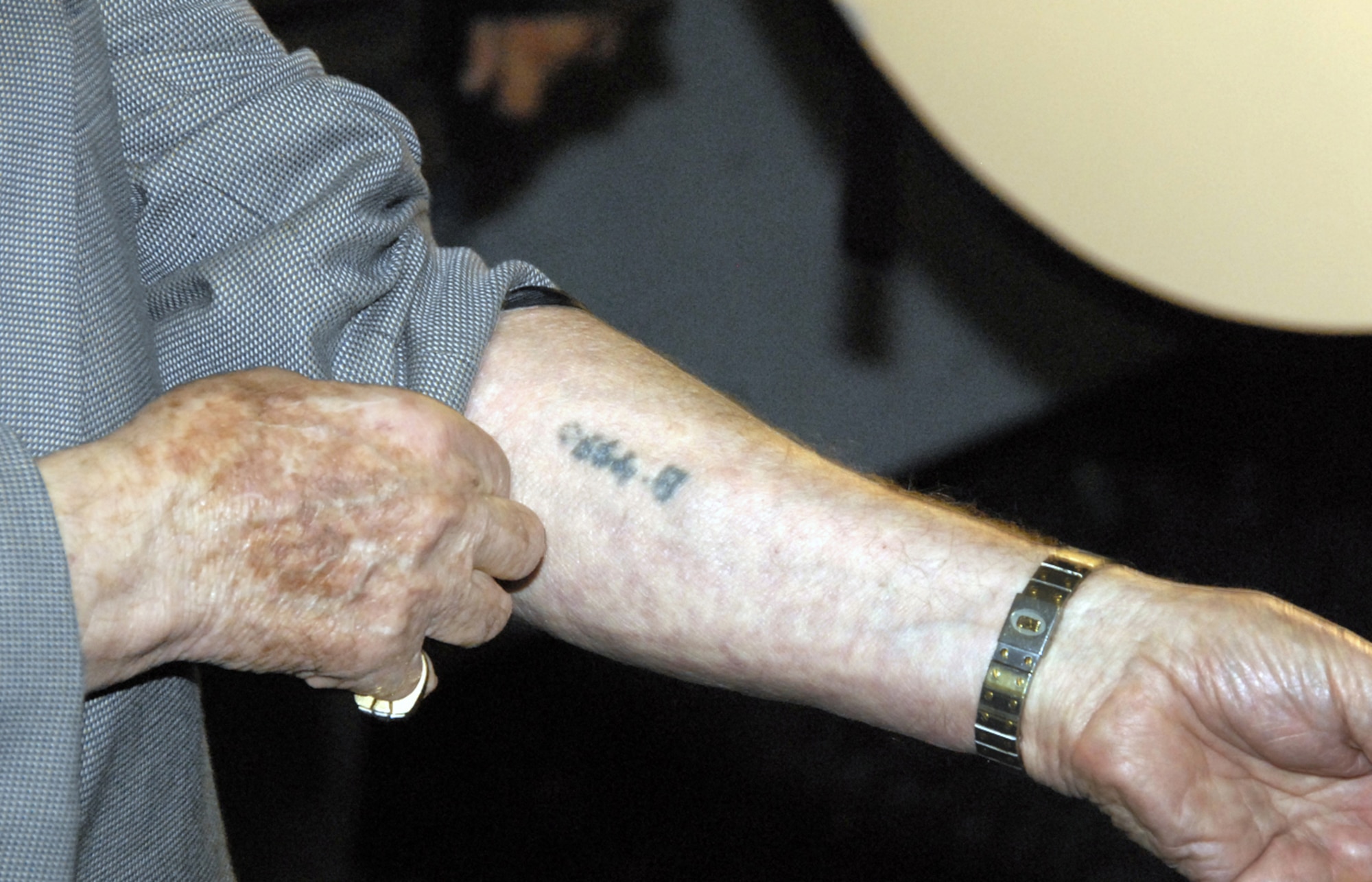 Michael Jacobs, a Holocaust survivor, shows attendees of the April 17 Sheppard Air Force Base Holocaust Rememberance Luncheon the marks imprinted on him during his time in the Nazi concentration camps. (U.S. Air Force photo/Sandy Wassenmiller)