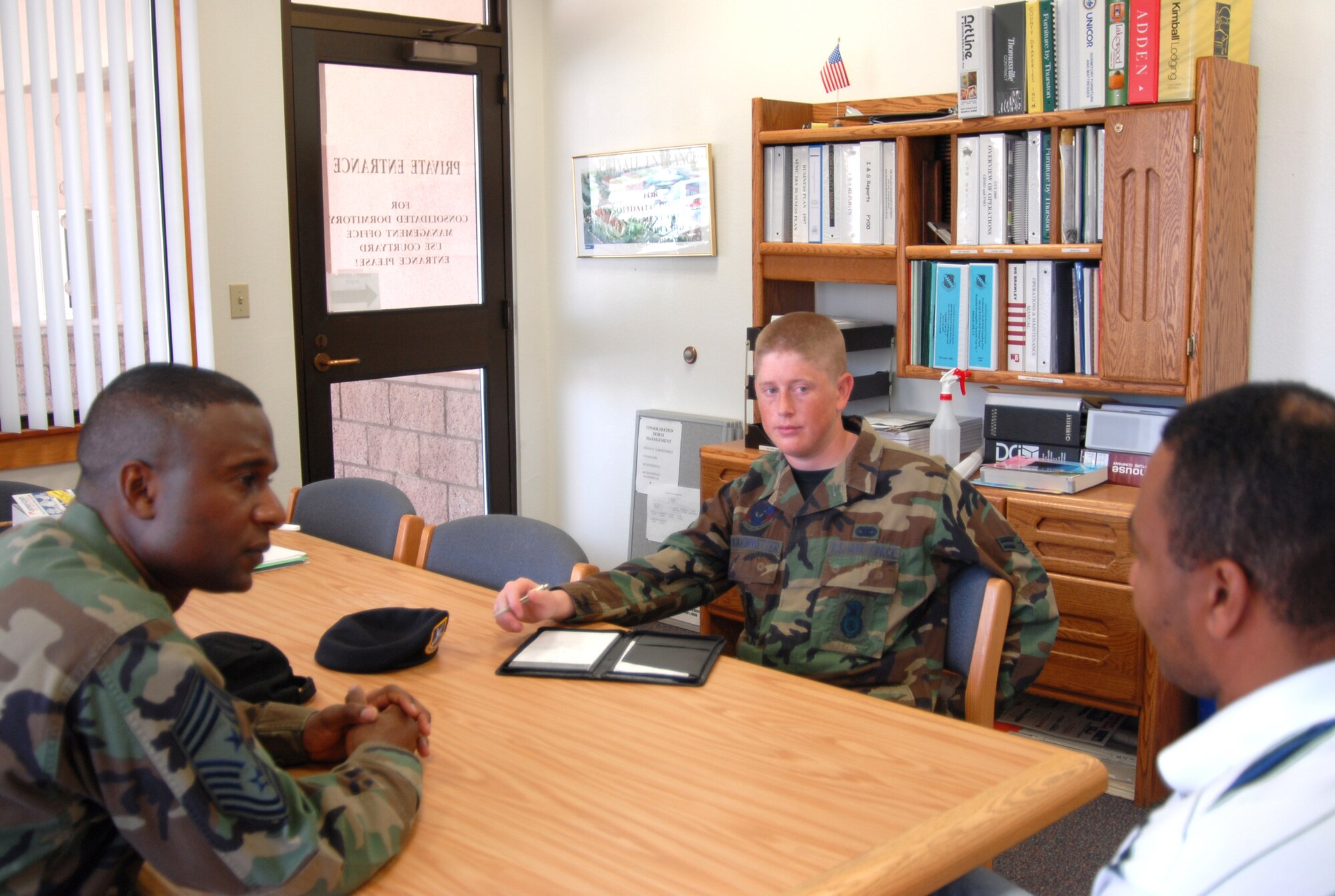 Chief Master Sgt. Juan Lewis, 95th Air Base Wing command chief, and honorary command chief, Airman 1st Class Michael Schoenwetter, a 95th Security Forces Squadron apprentice, speak with Kevin Jones, the Consolidated Dorm Management Office manager about dormitory issues at Edwards. (Photo by Airman 1st Class Stacy Sanchez)