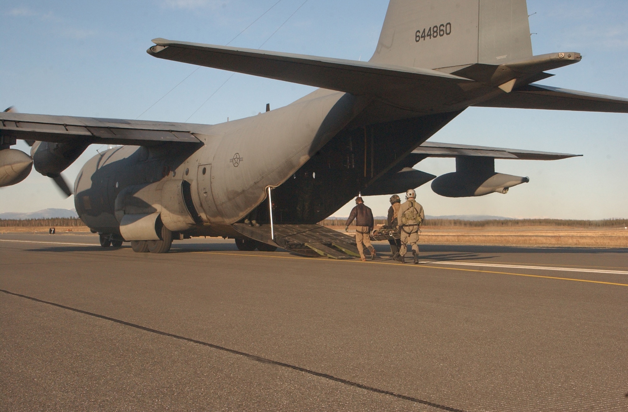 An aerial gunner and two pararescuemen off-load an injured aircrew member from a HH-60 Pave Hawk onto a C-130 during a combat search and rescue training mission at Red Flag-Alaska 07-1. Airmen from the 79th Rescue Squadron at Davis-Monthan Air Force Base, Ariz., operate the HC-130, which is known for providing rapidly deployable combat search and rescue forces to theater commanders worldwide. (U.S. Air Force photo by Senior Airman Justin Weaver). 