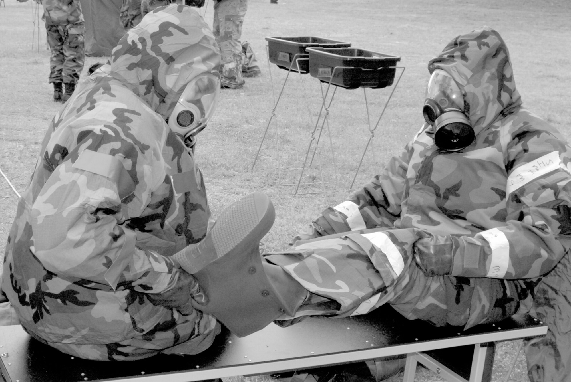 Senior Airman Milton White helps Staff Sgt. Deotha Akins take her chemical boots off during a base exercise Wednesday. 