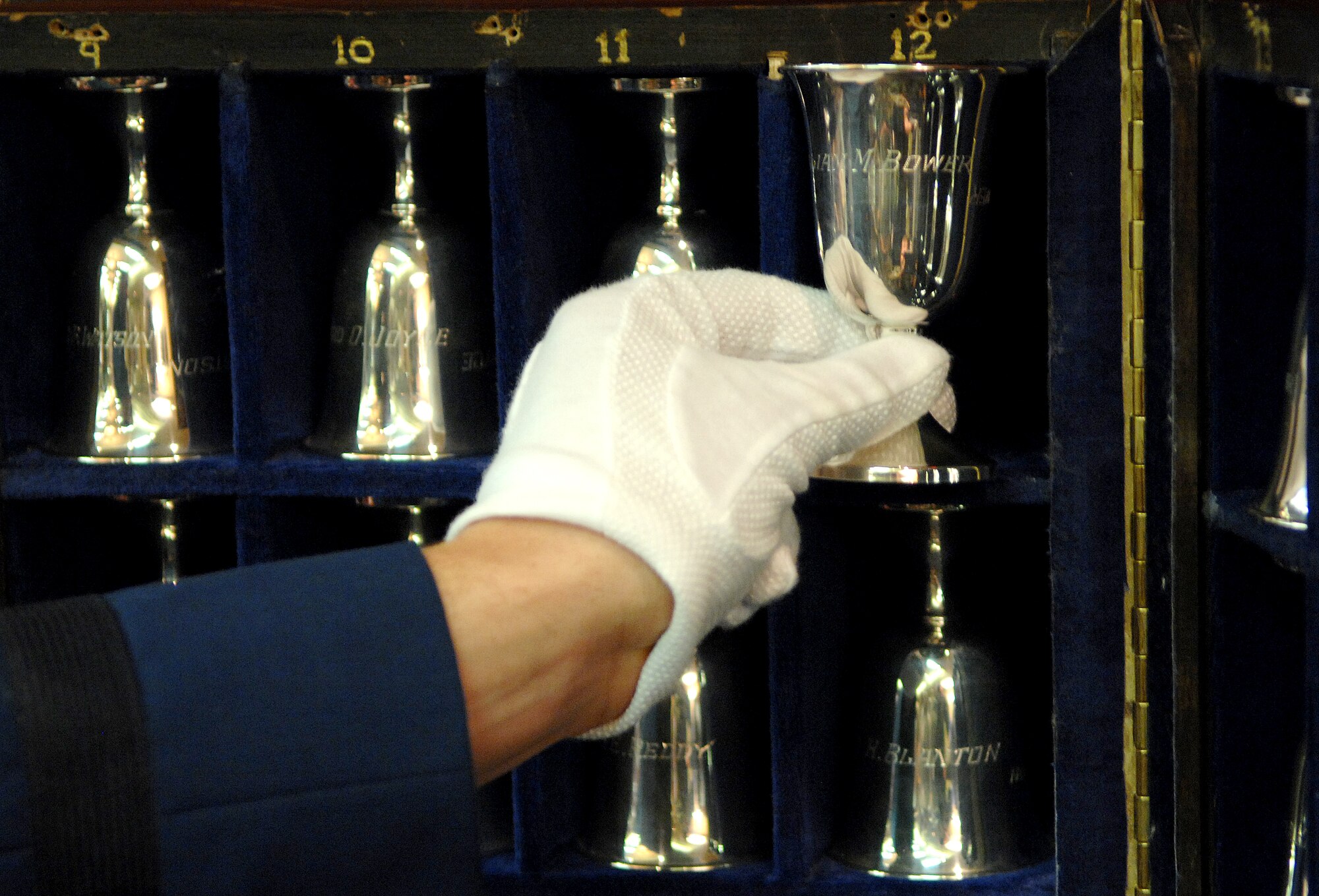 Cadet 1st Class Scott Crellin removes a goblet from its case during a goblet ceremony April 18 in San Antonio.  This reunion marks the 65th Anniversary of the Tokyo Raid in 1942. There are 80 goblets representing all 80 Doolittle Raiders. When a Raider dies, his goblet is turned over in the case. (U.S. Air Force photo/Staff Sgt. Brian Ferguson)