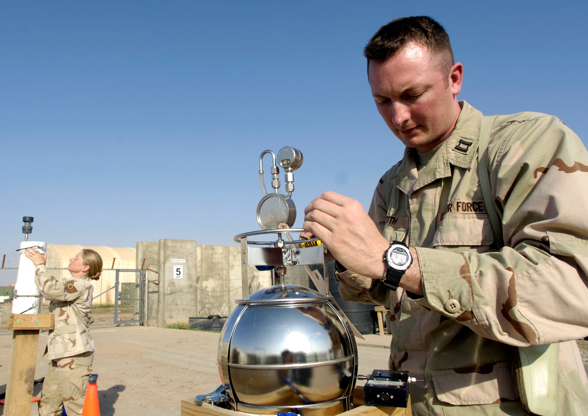 Capt. Charles Toth and Tech. Sgt. Melissa Saraiva check monitoring devices for common pesticides and other environmental hazardous chemicals in the air April 13 at Balad Air Base, Iraq.  (U.S. Air Force photo/Airman 1st Class Nathan Doza)