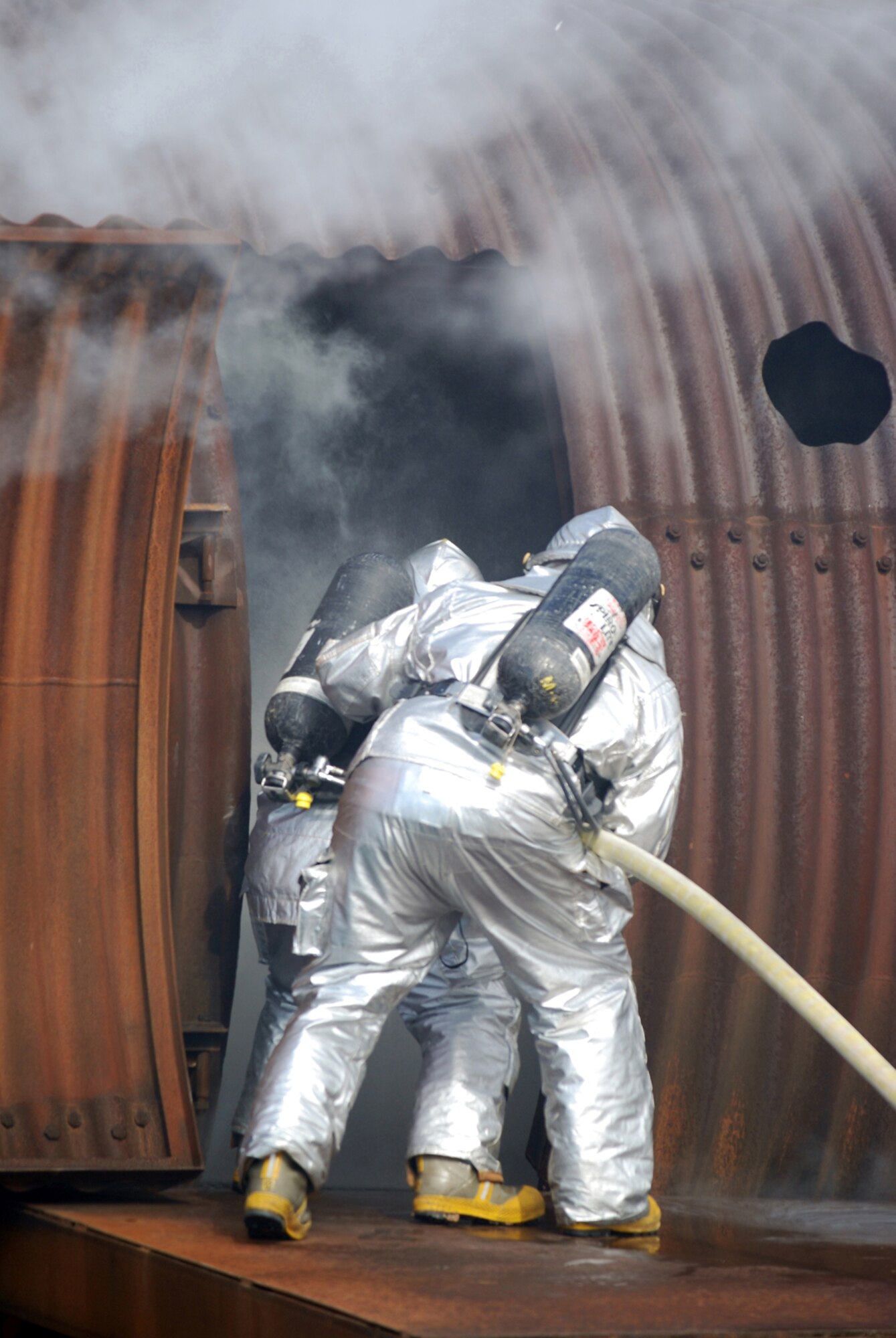 McConnell firefighters enter the fuselage of a burning aircraft simulator, April 11, during a live-fire training exercise on base. Firefighters from the 22nd Civil Engineer Squadron and the Kansas Air National Guard participated in the exercise. (Photo by Airman 1st Class Jessica Lockoski)