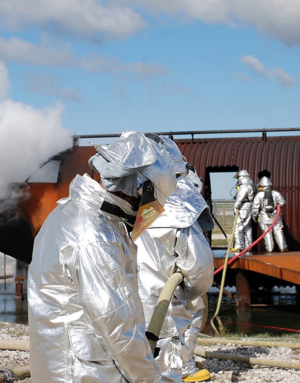 McConnell firefighters extinguish a fire in the cockpit of a mach aircraft, April 11, during a live-fire training exercise on base. Firefighters from the 22nd Civil Engineer Squadron and the Kansas Air National Guard participated in the exercise. (Photo by Airman 1st Class Jessica Lockoski)
