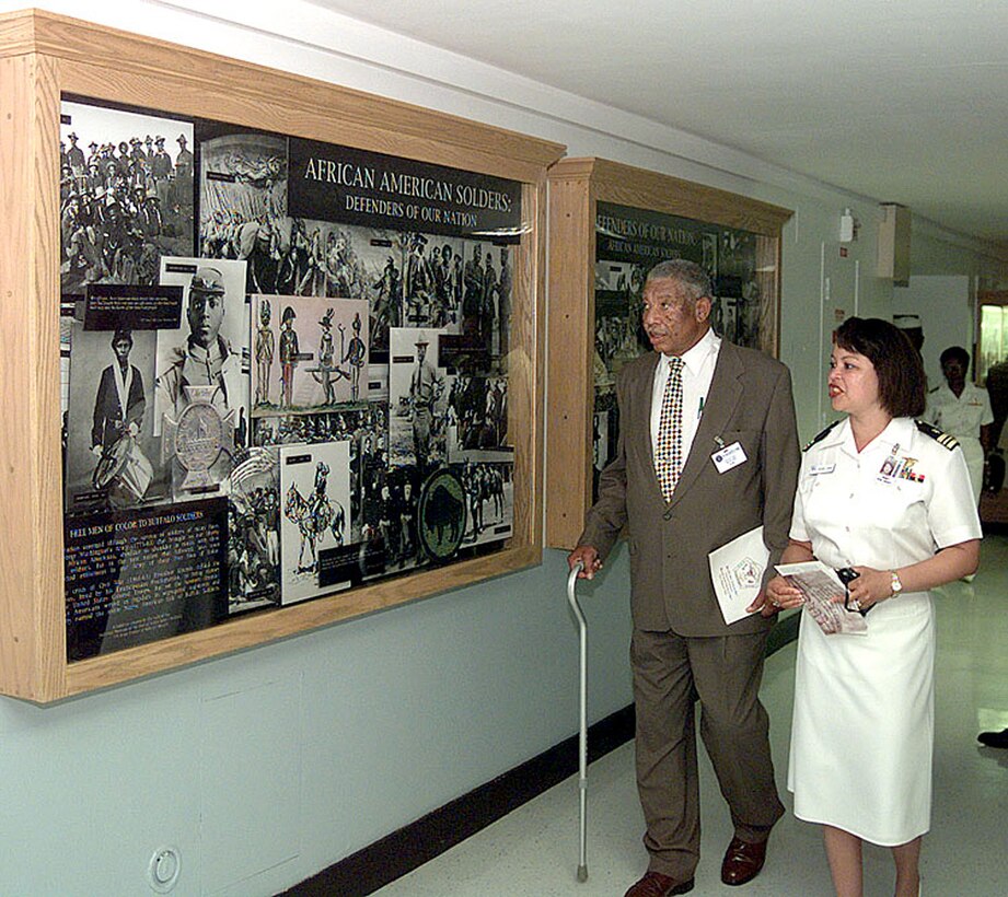 Retired Vice Adm. Samuel Gravely, the Navy's first black flag officer, strolls past an exhibit of the first African-American West Point graduate, the Buffalo Soldiers and African Americans who fought in the Revolutionary War and Civil War. Gravely's escort was Navy Lt. Cmdr. Desiree Linson who works for the assistant secretary of the Navy for manpower and reserve affairs. Rudi Williams