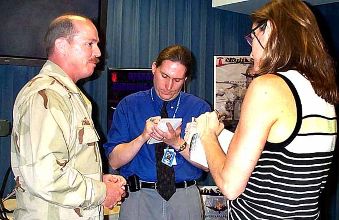 Army Master Sgt. Steve Longan (from left)  chats with Associated Press reporter Matt Kelly and United  Press International reporter Pam Hess at the Pentagon.  Longan served as a Special Forces A team member for about  five months in Afghanistan. The tour included working with  unexploded ordnance, hunting for enemy caves and weapon  caches and scouting potential air raid targets. Photo by  Linda D. Kozaryn.