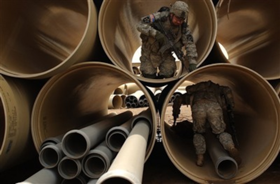 U.S. Army Staff Sgt. Larry Clapper (top) and Spc. Christopher Dodson search sewage pipes for suspicious materials during a combined cordon and search with the Iraqi army in Mansour, Iraq, on April 14, 2007.  Clapper and Dodson are from Alpha Company, 1st Battalion, 23rd Infantry Regiment, 3rd Stryker Brigade Combat Team, 2nd Infantry Division.  