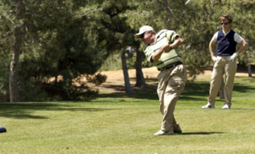 Todd Keegan tees off while his teammate Maureen McAllen, both from Fourth Air Force, watches. March Air Reserve Base captured the winner’s trophy at Broken Shaft Golf tournament against the Greater Riverside Chambers of Commerce. The Broken Shaft Tournament is an annual event between the two teams and this year, 52 people participated.  The base ended eight strokes ahead taking the low net total with 1903.  (U.S. Air Force photo by Staff Sgt. Amy Abbott, 452 AMW)