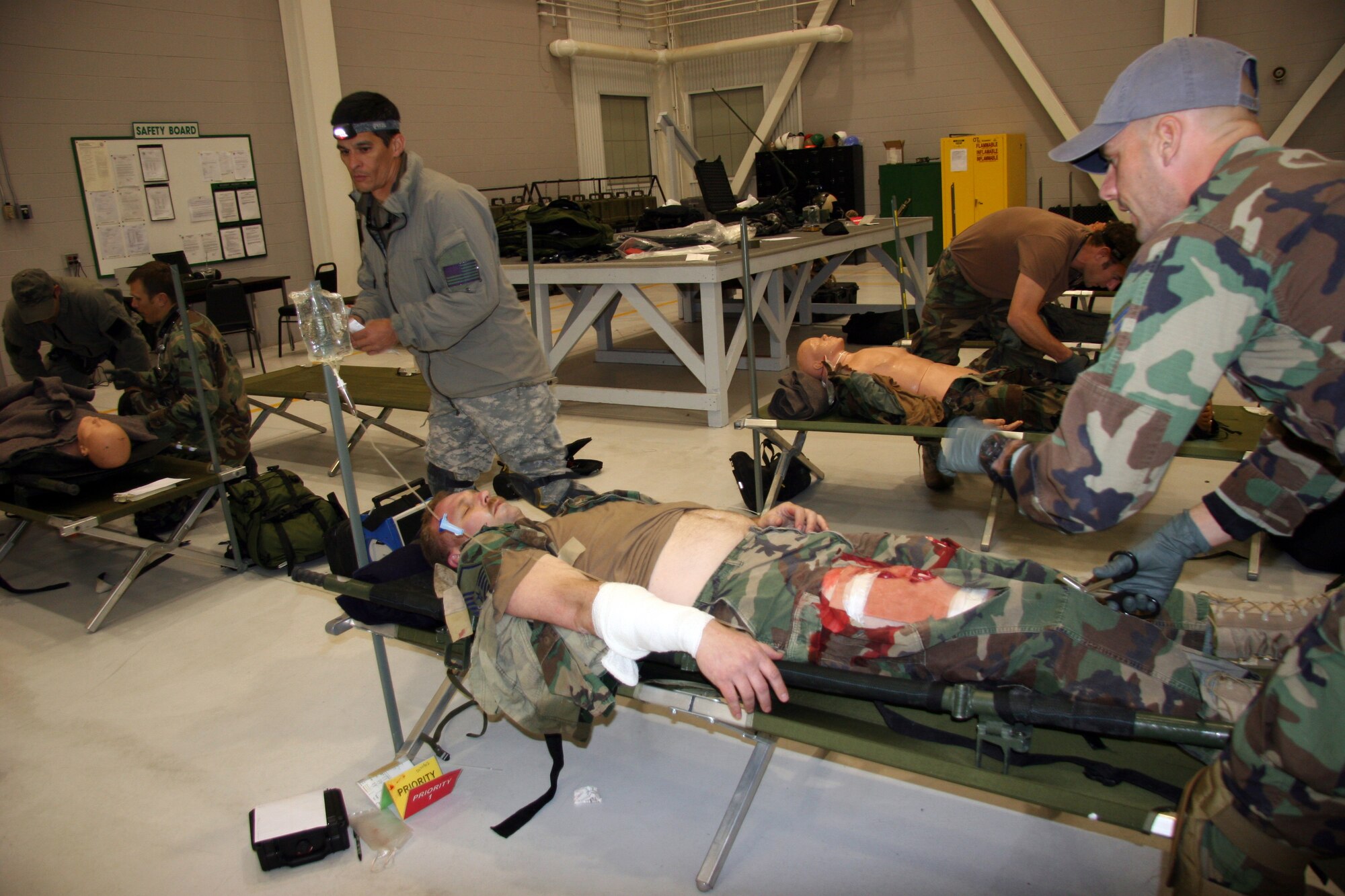 Senior Master Sgt. Tim Lum (left) and Airman 1st Class Jason Dykstra, 304th Rescue Squadron pararescuemen transport a helicopter crash survivor, Tech. Sgt. Aron Stine, 304th RQS training manager, to a higher level of medical care set up in the Oregon Army National Guard base hanger in Pendleton, Ore. during a nighttime mass casualty training exercise, April 17, 2007.  During the two-day training exercise, the pararescuemen practiced combat rescue scenarios, emergency medical care and patient transfer.  (U.S. Air Force Photo/Master Sgt. Ruby Zarzyczny)