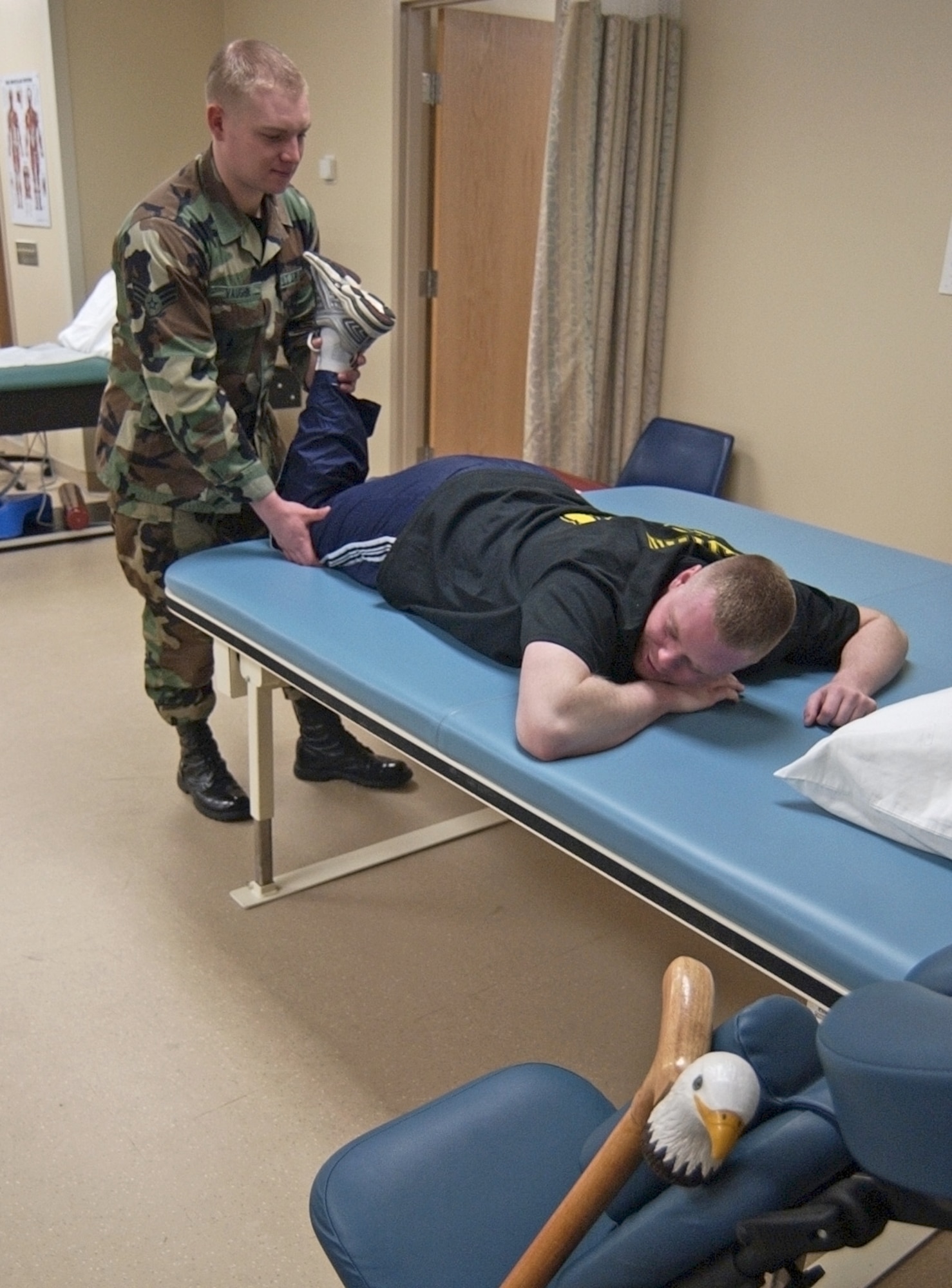 WRIGHT-PATTERSON AIR FORCE BASE, Ohio -- Senior Airman Chris Vaughn, a physical medicine technician at the Wright-Patterson Medical Center, helps Army Spc. Thomas Lewis with leg exercises April 13.  Lewis was injured in a vehicle crash in Iraq.  (U.S. Air Force/Spencer P. Lane)