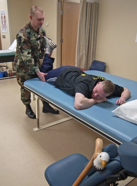 WRIGHT-PATTERSON AIR FORCE BASE, Ohio -- Senior Airman Chris Vaughn, a physical medicine technician at the Wright-Patterson Medical Center, helps Army Spc. Thomas Lewis with leg exercises April 13.  Lewis was injured in a vehicle crash in Iraq.  (U.S. Air Force/Spencer P. Lane)