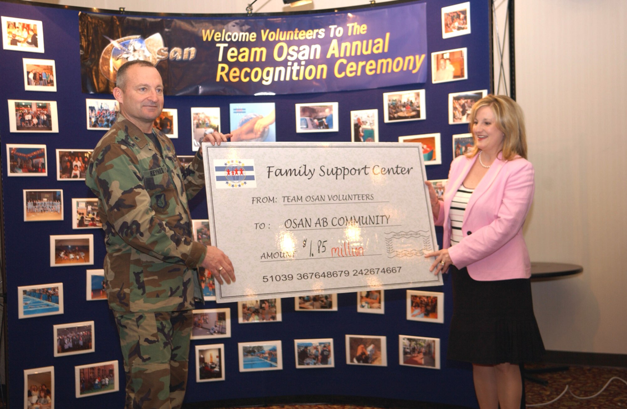 OSAN AIR BASE, Republic of Korea -- Brig. Gen. Joe Reynes, 51st Fighter Wing commander, and Mrs. Sherri Kitchens, Airman and Family Readiness Center community readiness technician, use a check to show how much volunteer's here saved the base. (U.S. Air Force photo by Staff Sgt. Ronald Hill)