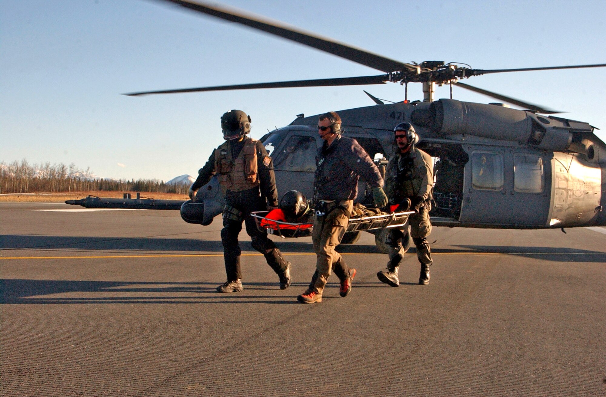 An aerial gunner and two pararescuemen off-load a simulated, injured aircrew member from a HH-60 Pave Hawk onto a HC-130 Hercules during a combat search and rescue training mission April 17 at Eielson Air Force Base, Alaska. Airmen from the 79th Rescue Squadron at Davis-Monthan Air Force Base, Ariz., are operating the HC-130 during a combat search and rescue mission at Red Flag-Alaska 07-1. (U.S. Air Force photo\Senior Airman Justin Weaver)