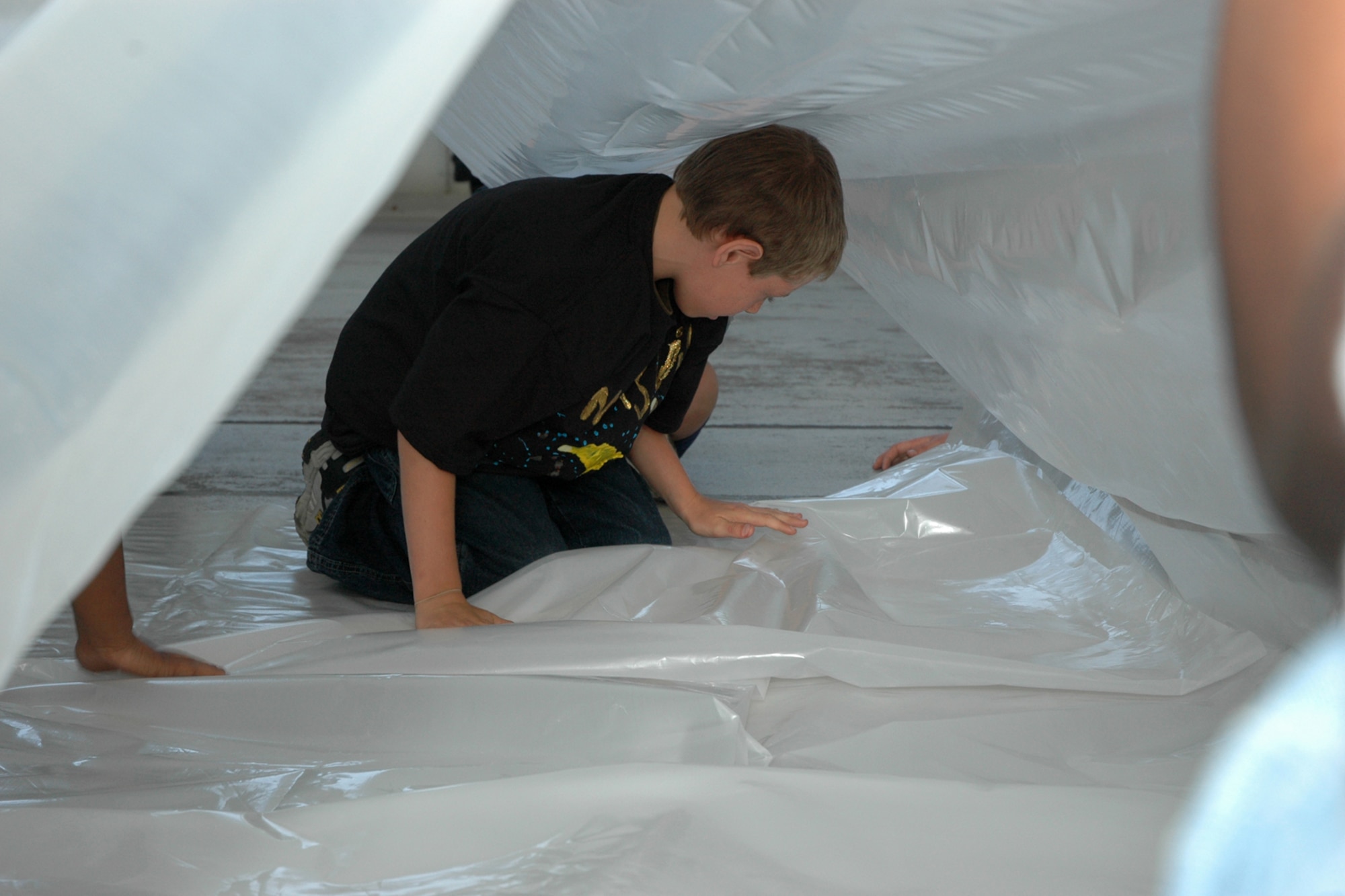EGLIN AIR FORCE BASE, Fla. -- Merle Thumma, 11, a fifth grader from Longwood Elementary, folds the plastic shelter into place during Marsville April 20 inside Hangar 110.The folds were in preparation for inflating the plastic shelter. Fifth-grade students from three elementary schools kicked off the Marsville Project culminating six weeks of study about space. The project required students from Cherokee, Valparaiso and Longwood Elementary Schools to experience a day of living in "space" by building a habitat. During the weeks prior to Marsville, students learned about the life support systems to consider before travel into space, such as the need for air, water, transportation and garbage disposal. Each student built a life support system model to bring with them. (U.S. Air Force photo by Staff Sgt. Mike Meares)
