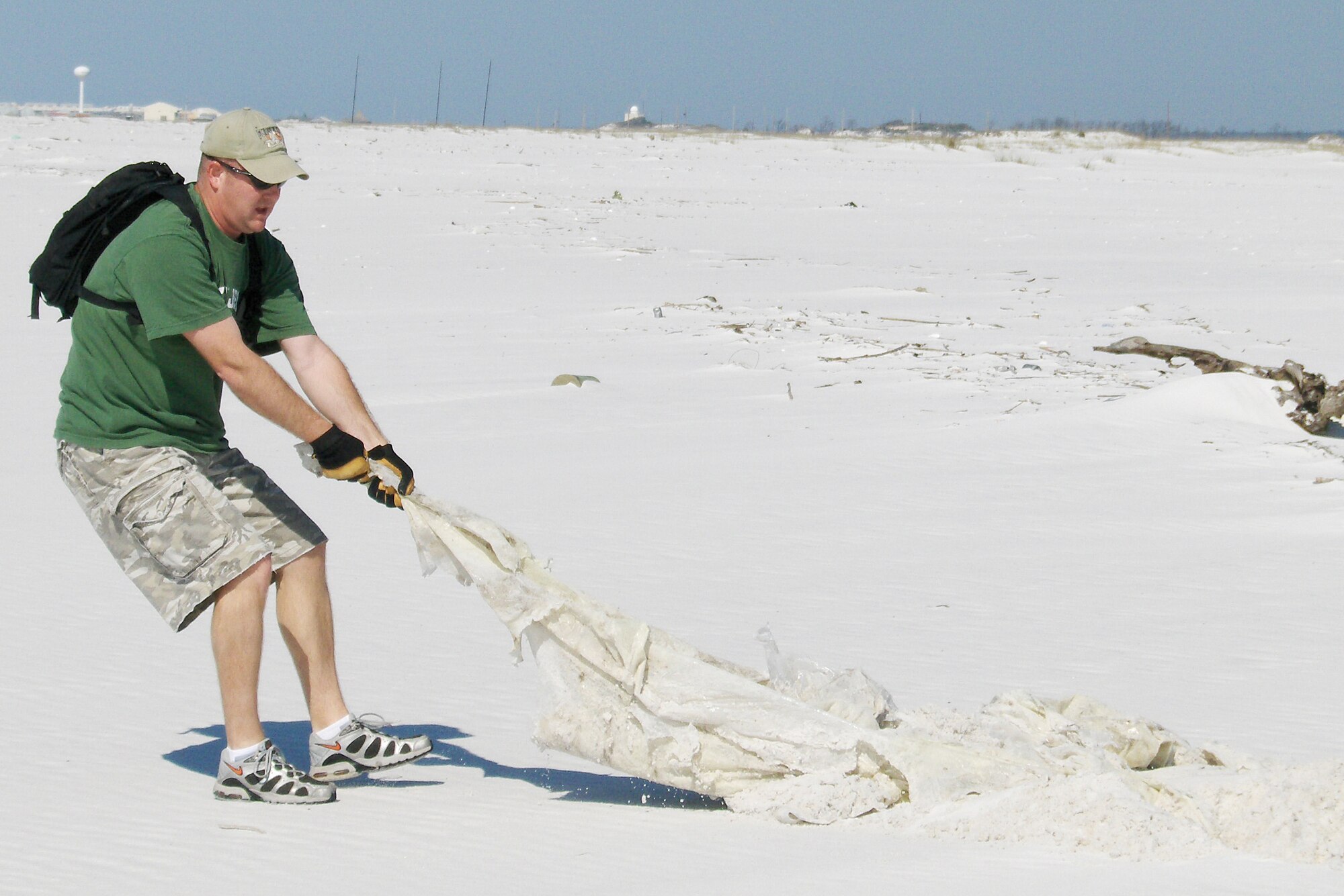 EGLIN AIR FORCE BASE, Fla. -- Tech. Sgt. Jerry Schultz, 46th Aircraft Maintenance Squadron's Red Aircraft Maintenance Unit specialist section flight chief, pulls a plastic tarp off an area on Eglin's restricted beach. More than 90 volunteers from the Eglin community picked up more than 13,000 pounds of trash and debris over approximately 14 miles of Eglin restricted beach area in celebration of Eglin Earth Day April 19.