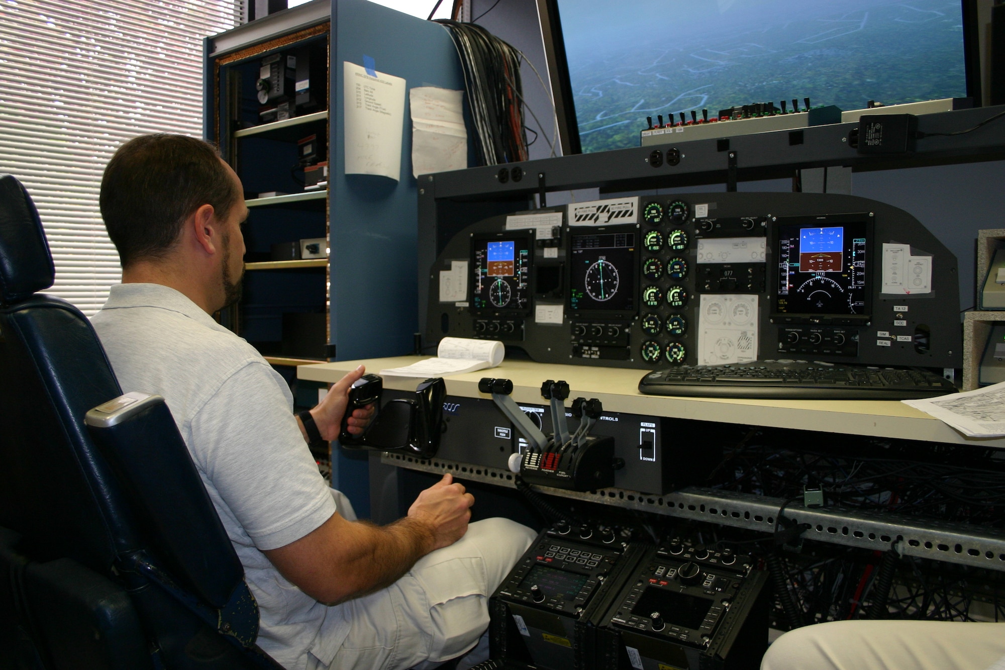 Test subject Stephen J. Richard, deputy chief of the Defense Attaché System Air and Maritime, pilots a C-12 cockpit mock-up during an assessment of the aircraft’s Primary Flight References. Joint Cockpit Office researchers record data to ensure the information the pilot receives from the instruments is correct.
