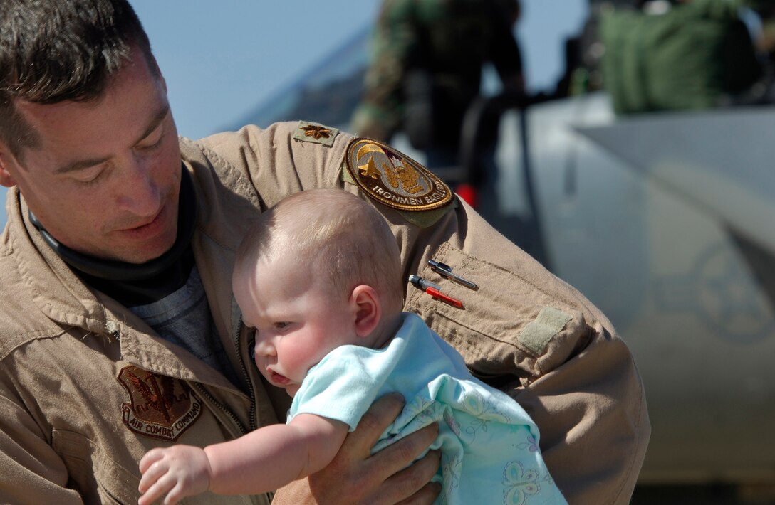 Maj. John Holovich, an F-15C Eagle pilot with the 71st Fighter Squadron, shares a moment with his daughter, Raegan, after returning from Exercise Iron Eagle, a joint multi-national exercise designed to provide training in a realistic combat environment. (U.S. Air Force Photo/Staff Sgt. Samuel Rogers)