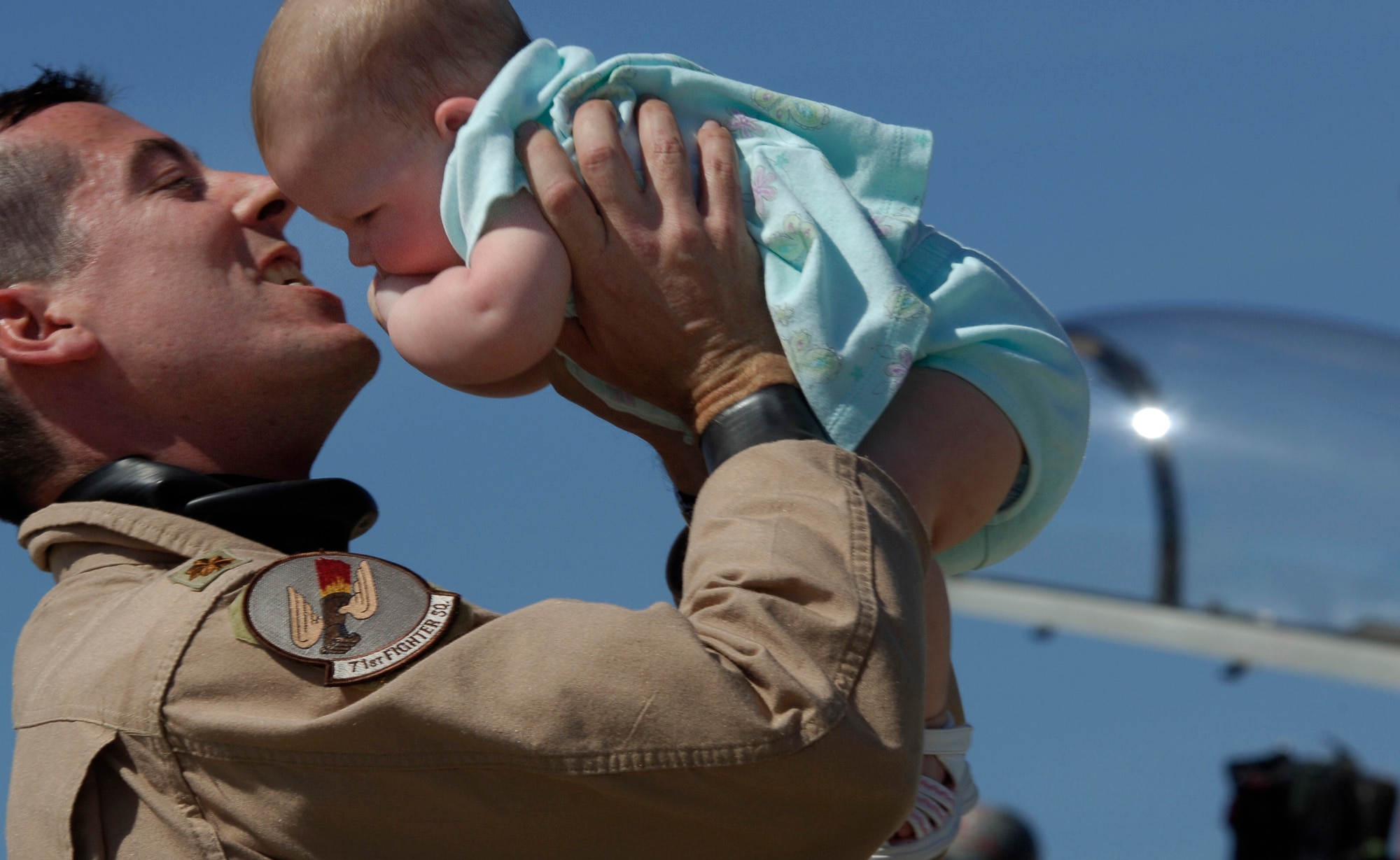 Maj. John Holovich, an F-15 Eagle pilot with the 71st Fighter Squadron, shares a moment with his daughter, Raegan, after his return from Exercise Iron Eagle, a joint multi-national exercise designed to provide intense training in a realistic combat environment. (U.S. Air Force photo/Staff Sgt. Samuel Rogers)