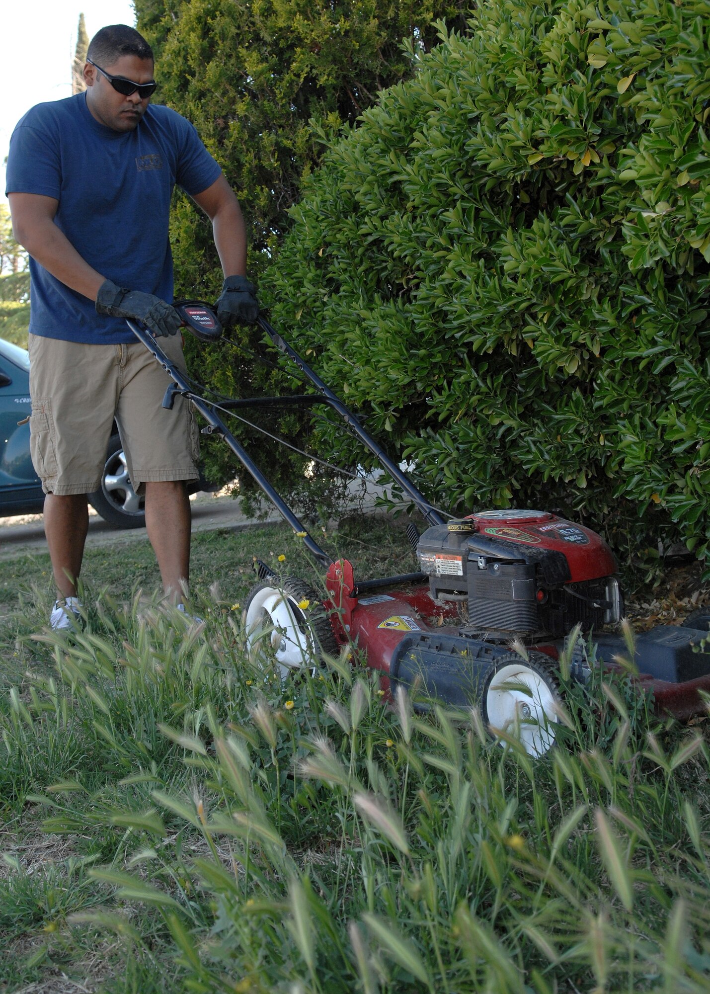 Staff Sgt. James Zannetti, 49th Communications Squadron, mows the lawn of a local resident as part of The Day of Caring event in Alamogordo April 20. The Day of Caring is an event in which Holloman Airmen give back to the community and help beautify the city.  (U.S. Air Force photo by Airman 1st Class John Strong)