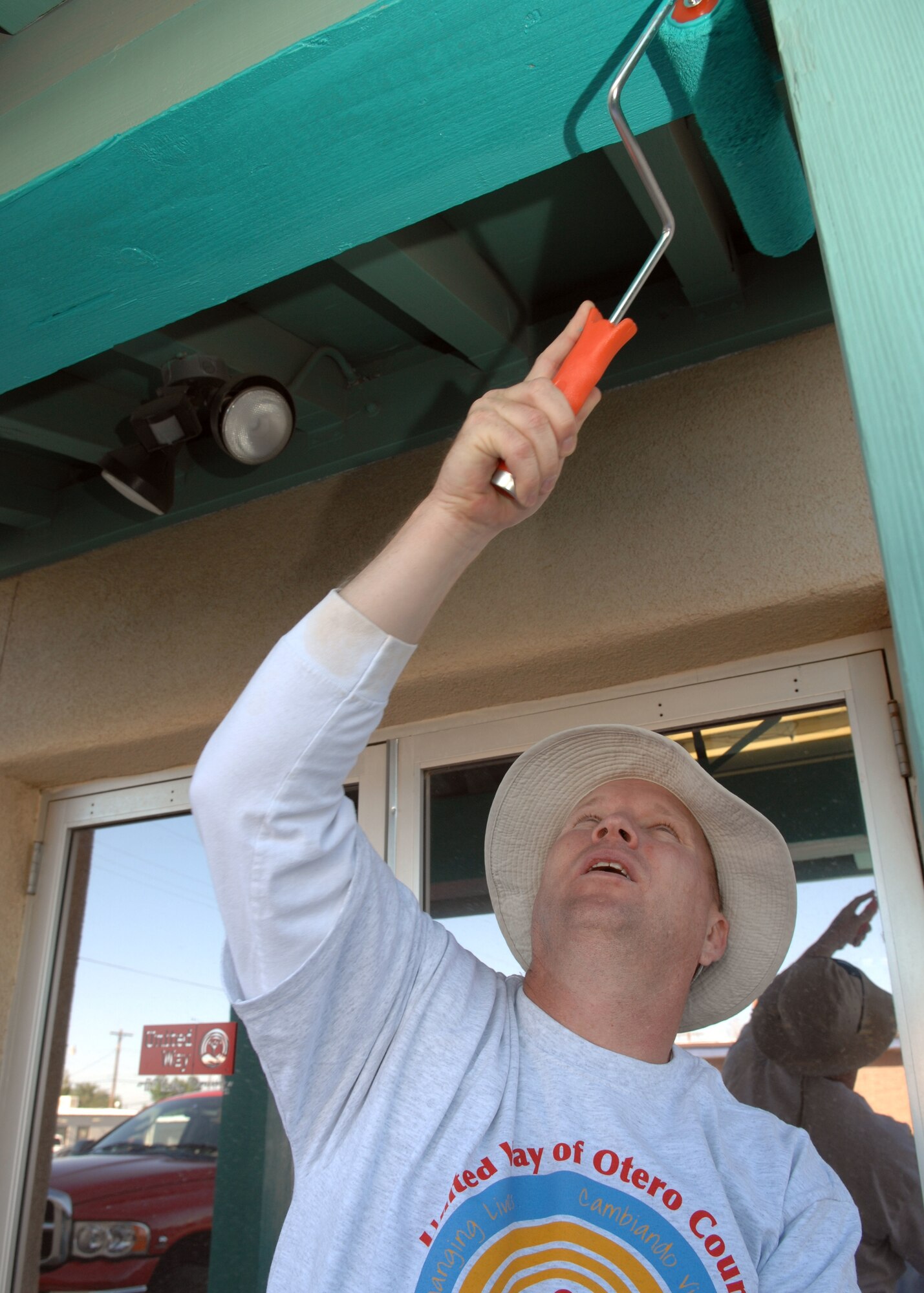 Staff Sgt. Timothy Bailey, 46th Test Group, paints a door canopy to United Way of Otero County April 20 in Alamogordo. Staff Sgt. Bailey has volunteered his time to help beautify the community as part of the Day of Caring event. (U.S. Air Force photo by Airman 1st Class Jamal Sutter)