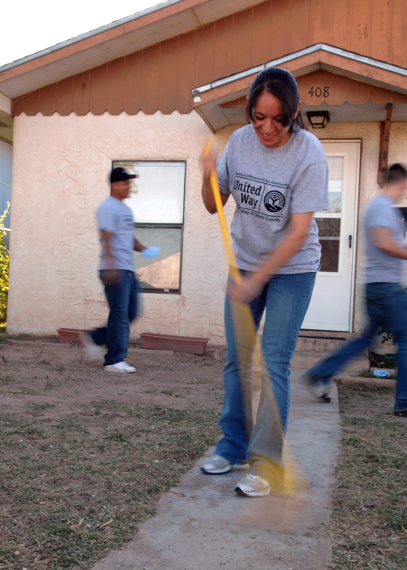 1st Lieutenant Julia Enriquez, 49th Logistics Readiness Squadron, sweeps the walkway for a local resident as part of The United Way of Otero County's Day of Caring event April 20 in Alamogordo. Day of Caring is an event that has Holloman Airmen and Alamogordo citizens doing odd jobs around the community. (U.S. Air Force photo by Airman 1st Class Jamal Sutter)