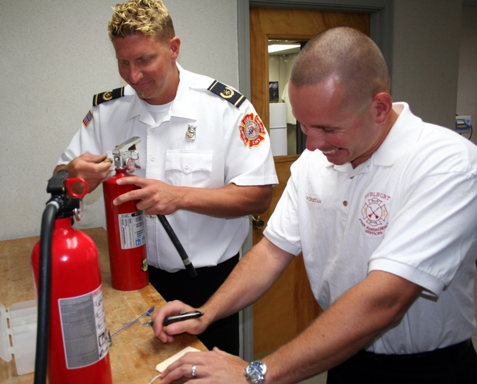 Don Savidge (left), 1st Special Operations Civil Engineer Squadron Fire and Emergency Services Flight, performs maintenance on a rechargeable fire extinguisher, while Hans Christian, also of the Fire and Emergency Services Flight, performs an inspection on a non-rechargeable extinguisher. They suggested that the Air Force start using only non-rechargeable extinguishers because they don't require maintenance every 6 years like rechargeable ones do. They were two of four civilians to win all of Hurlburt's first quarter IDEA awards. (U.S. Air Force photo by Staff Sgt. Angela Shepherd)