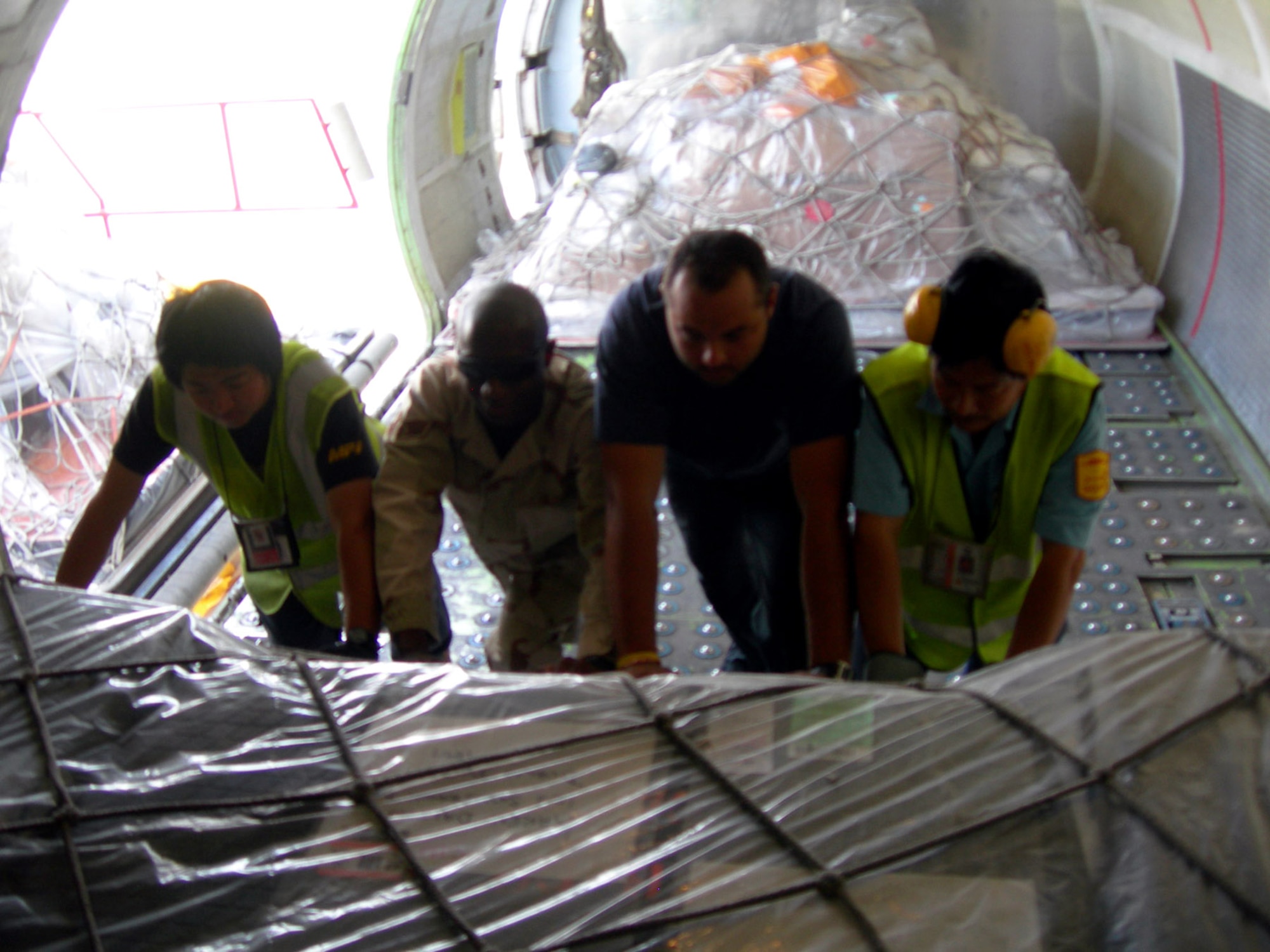 Senior Airman Kevin Goldman and contractors load outgoing mail onto a cargo aircraft at Balad Air Base, Iraq. The Joint Military Mail Terminal sends out approximately 85,000 pounds of outgoing mail each week. Every day two aircraft deliver and pick up an average of 18 pallets of mail to and from the base. Airman Reynolds is assigned to the 332nd Expeditionary Communications Squadron. (U.S. Air Force photo/Capt. Ken Hall)