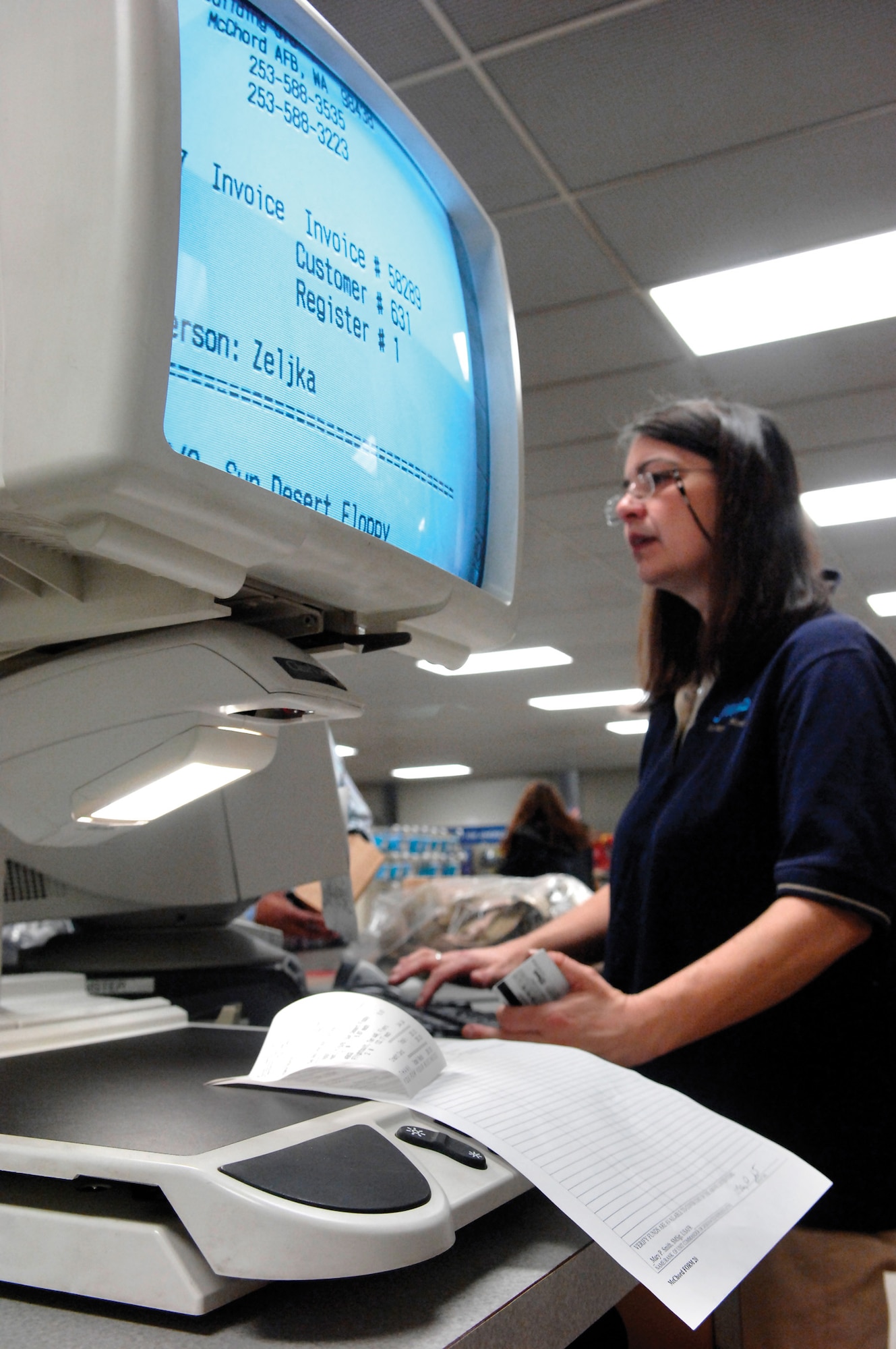 MCCHORD AIR FORCE BASE, Wash. --  Express Store employee Zeljka Harmon, who is legally blind, checks out a customer on April 16 using a product designed to enlarge printed material for people who have low vision and can no longer comfortably use glasses or special lenses to read regular size print. (U.S. Air Force photo/Abner Guzman)