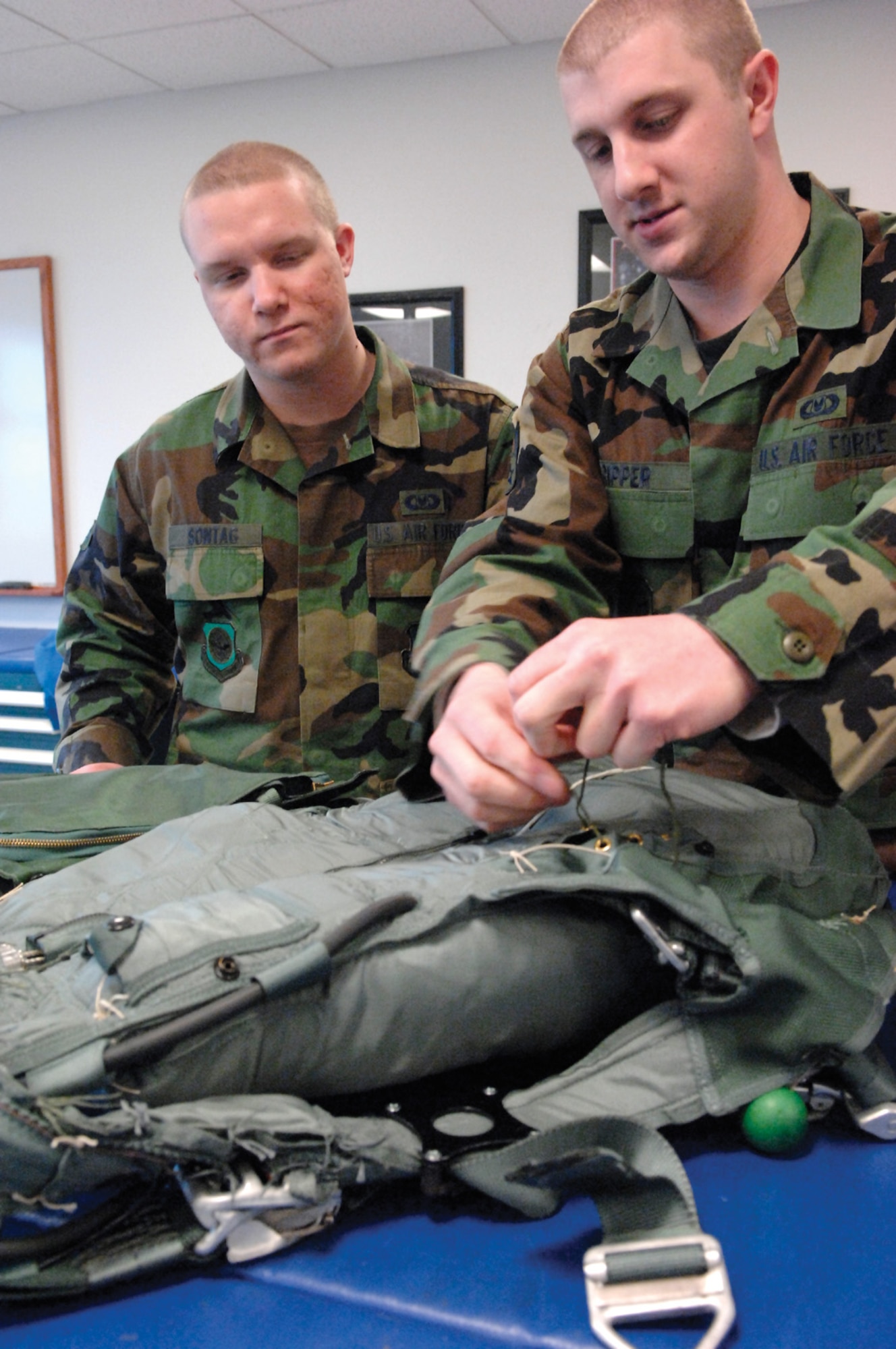 MCCHORD AIR FORCE BASE, Wash. -- Airmen Steven Sontag, left, and Joseph Ripper, both from the 62nd Operations Support Squadron, inspect a parachute  April 16, 2007 in the aircrew life support section warehouse prior to clearing it for pre-positioning aboard an aircraft. (U.S. Air Force photo/Abner Guzman)